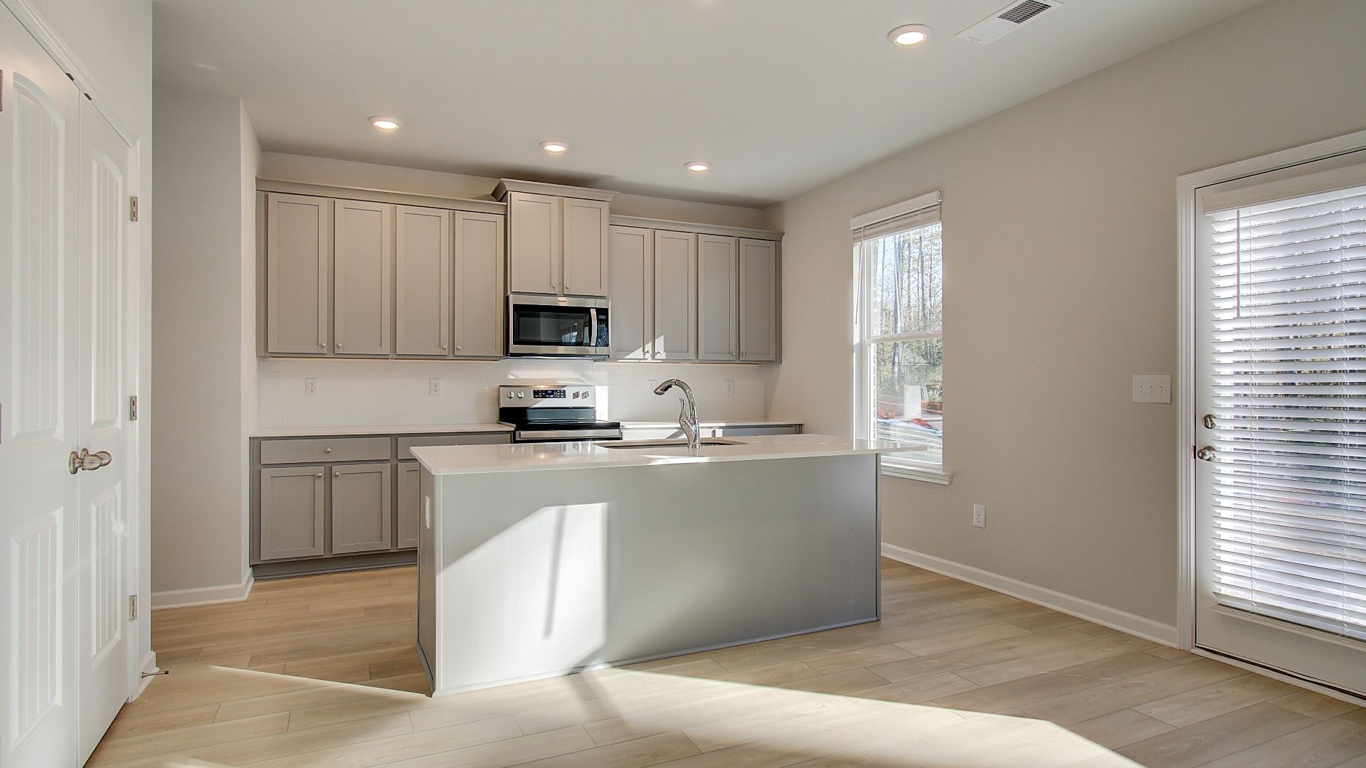 Open Pelham kitchen with center island, stainless appliances, and natural light at Bowers Farm in McDonough, GA.