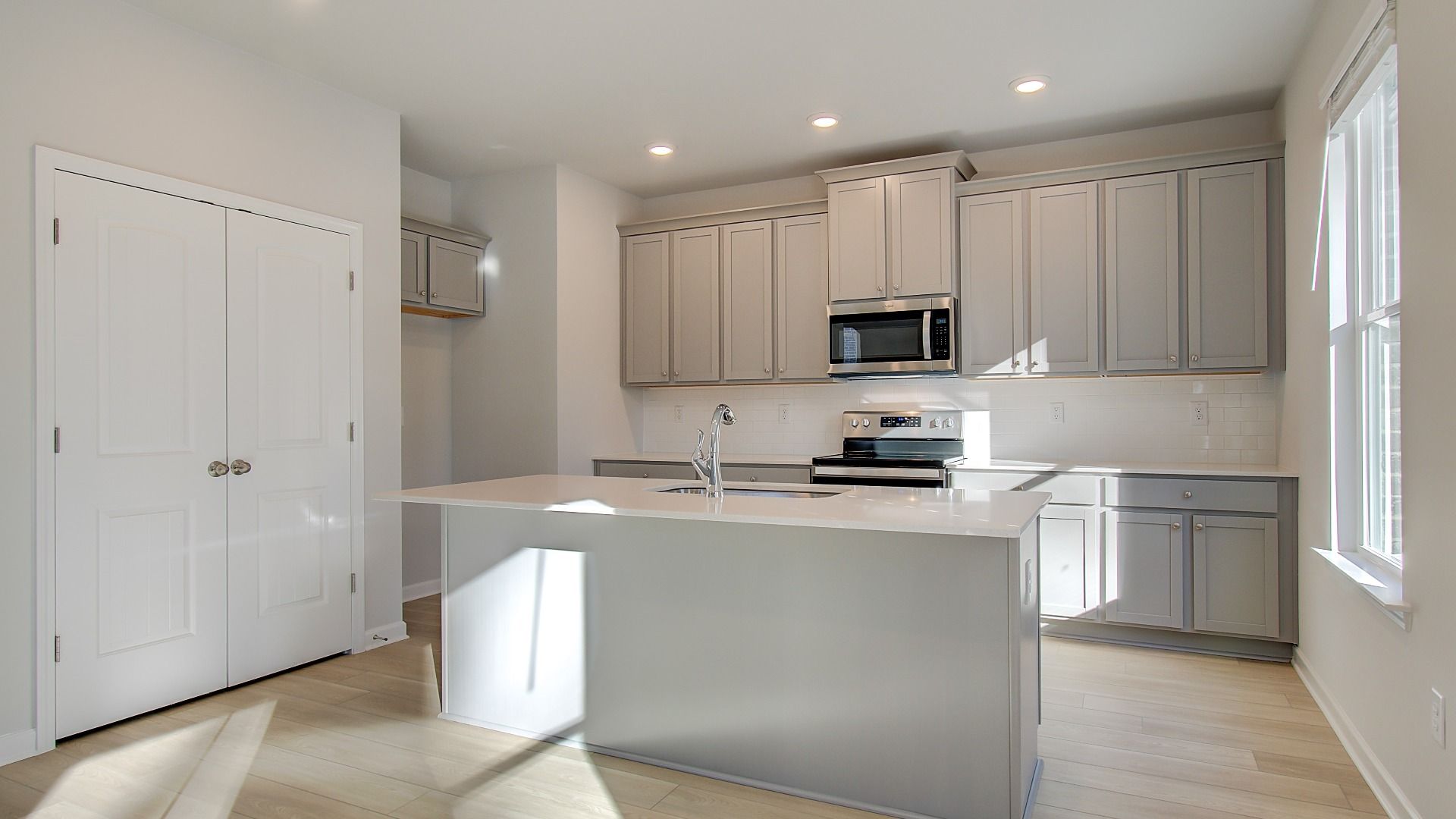 Open Pelham kitchen with center island, clean modern cabinetry, and stainless appliances at Bowers Farm in McDonough, GA.