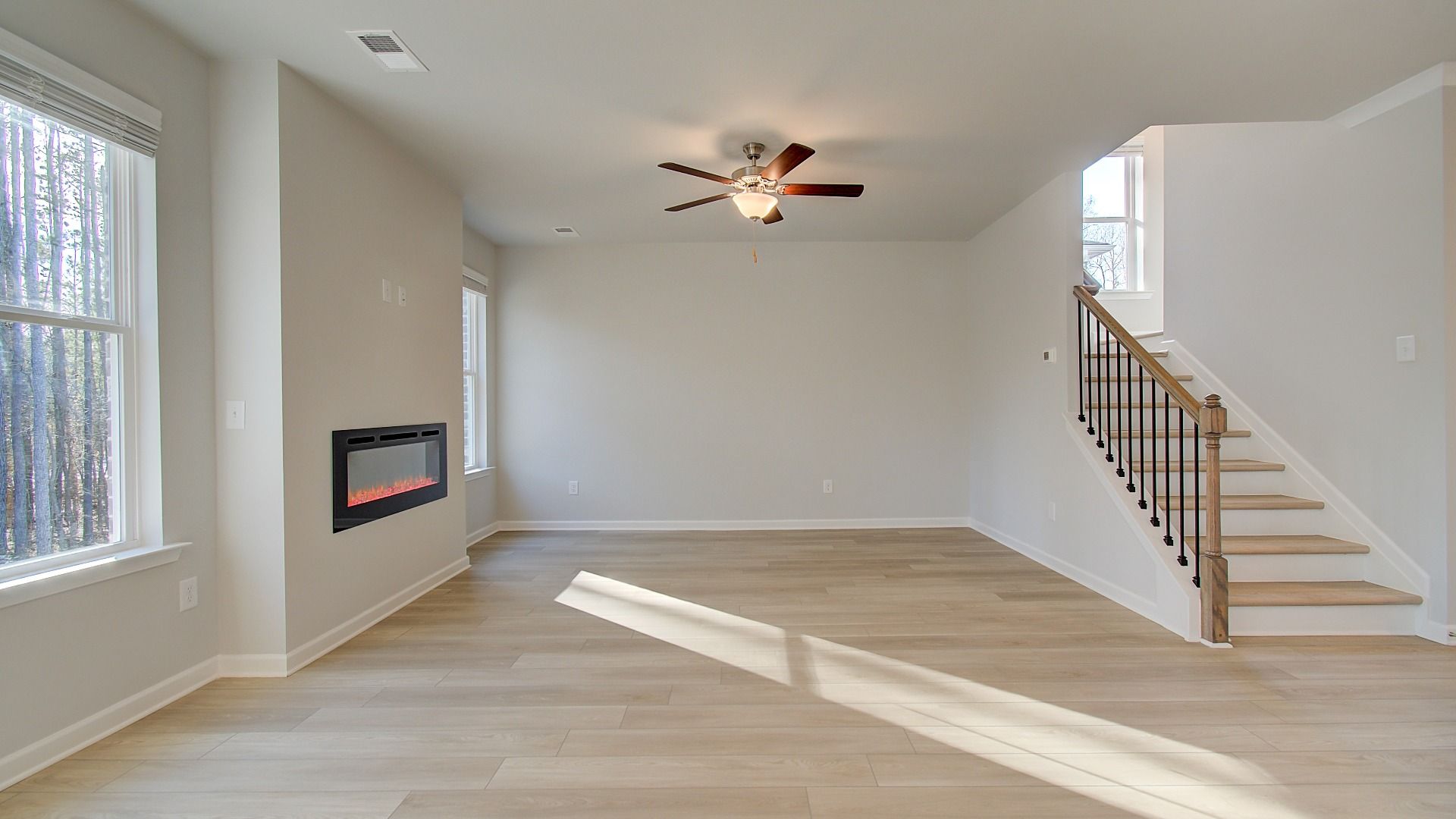 Spacious open Pelham family room with LVP flooring, center electric fireplace, and natural light at Bowers Farm.