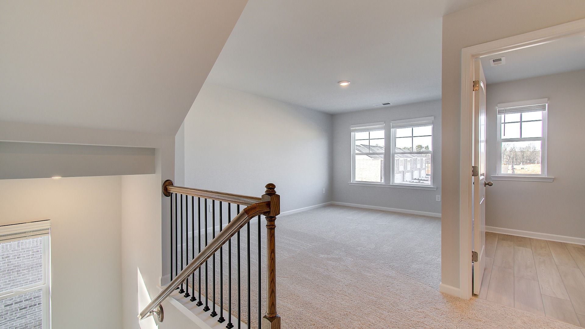 Spacious Pelham loft off staircase with abundant natural light and carpet flooring at Bowers Farm in McDonough, GA.