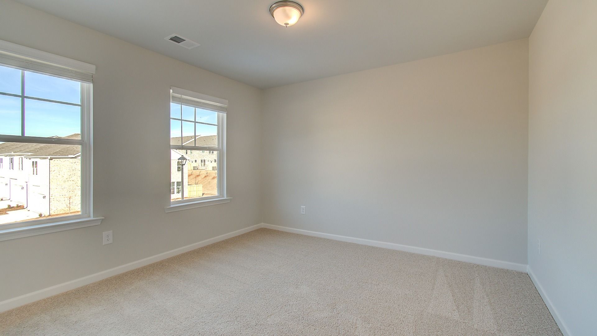 Generously sized secondary bedroom with overhead lighting, natural light, and carpet flooring in the Pelham at Bowers Farm.