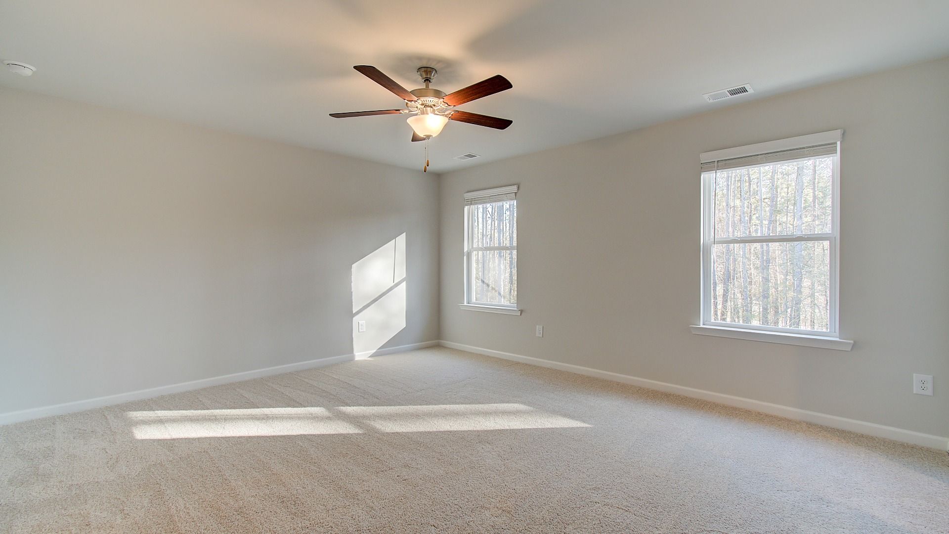Spacious primary suite with carpet flooring, natural light, and overhead fan light in the Pelham at Bowers Farm.