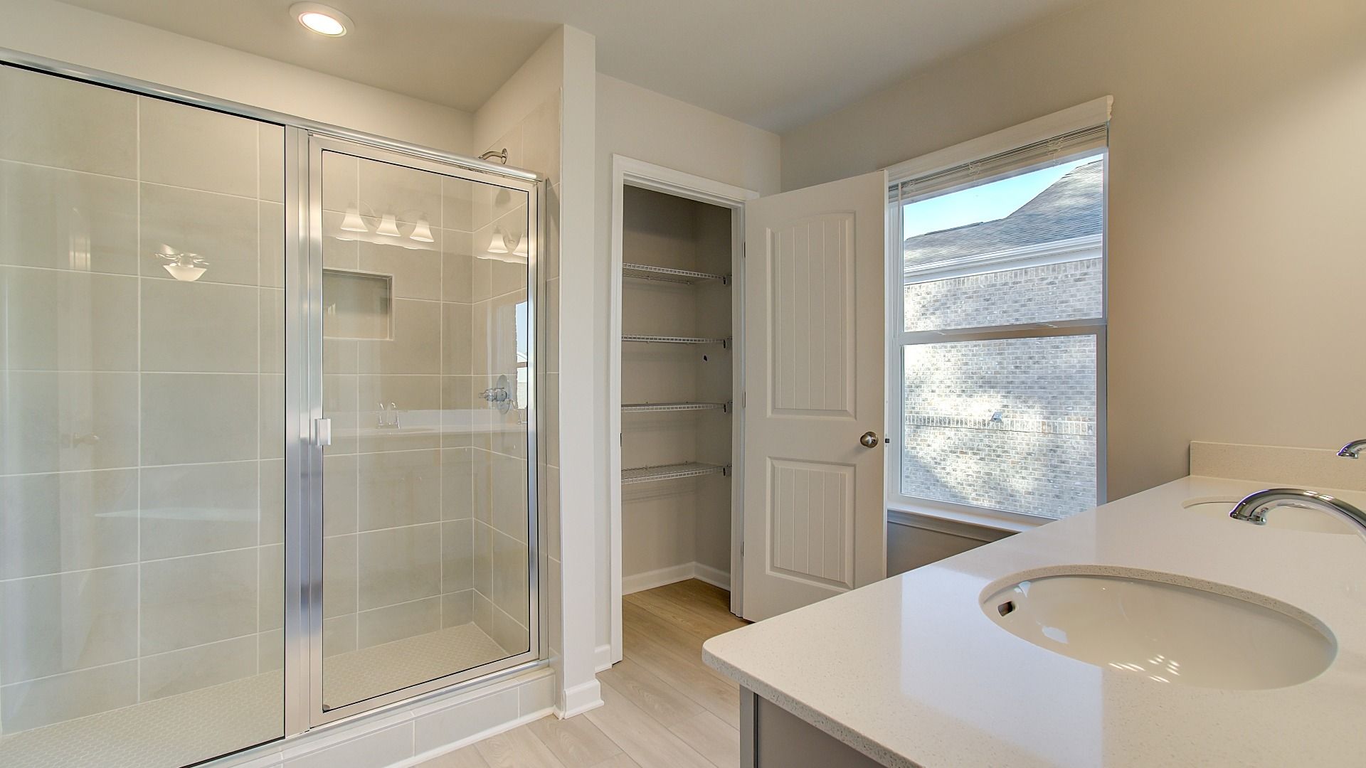 Primary bath with oversized walk-in shower, dual vanities, and side closet in the Pelham at Bowers Farm in McDonough, GA.