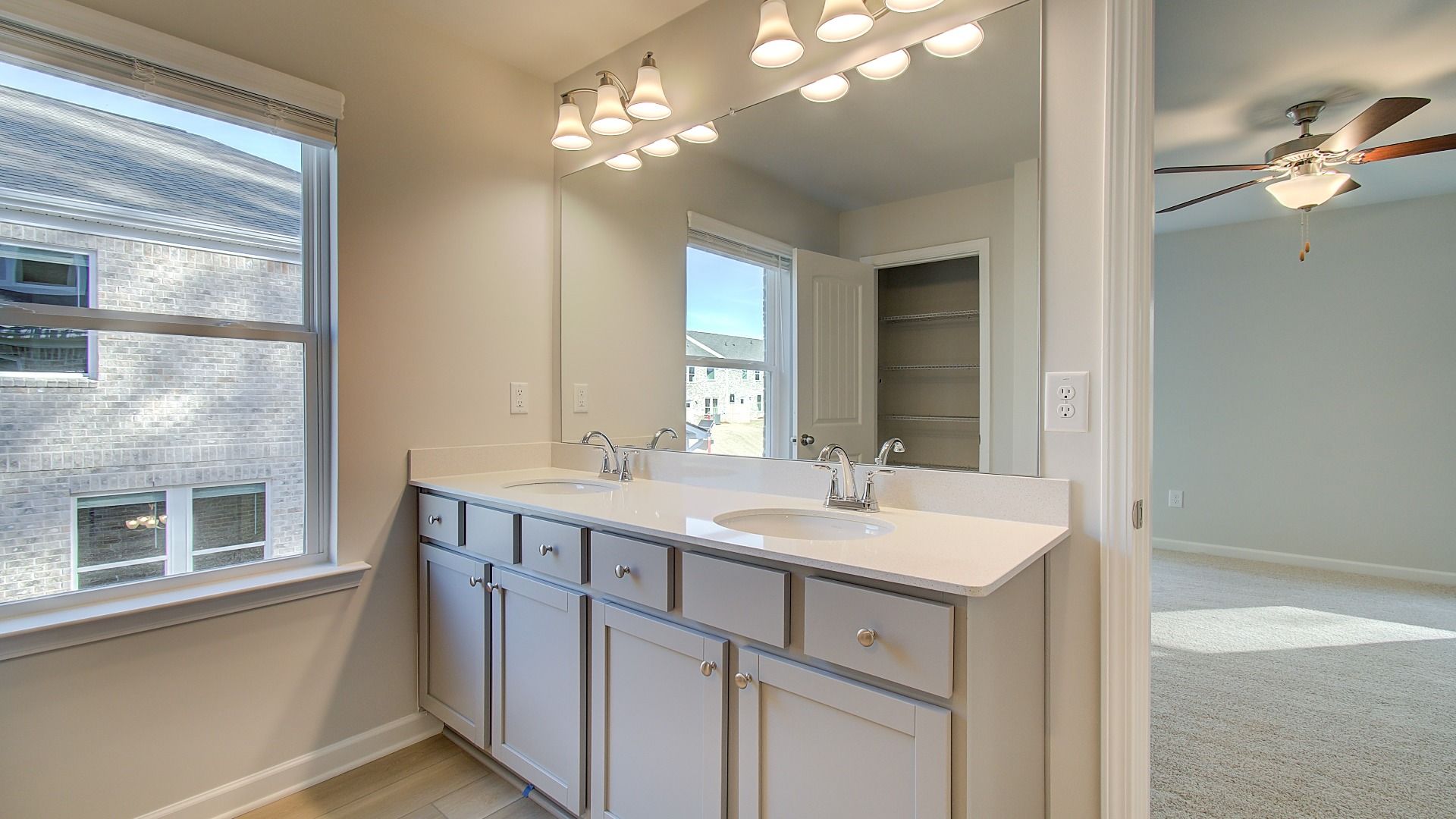 Primary bath with dual vanities and modern neutral finishes connecting to the primary suite in the Pelham at Bowers Farm.