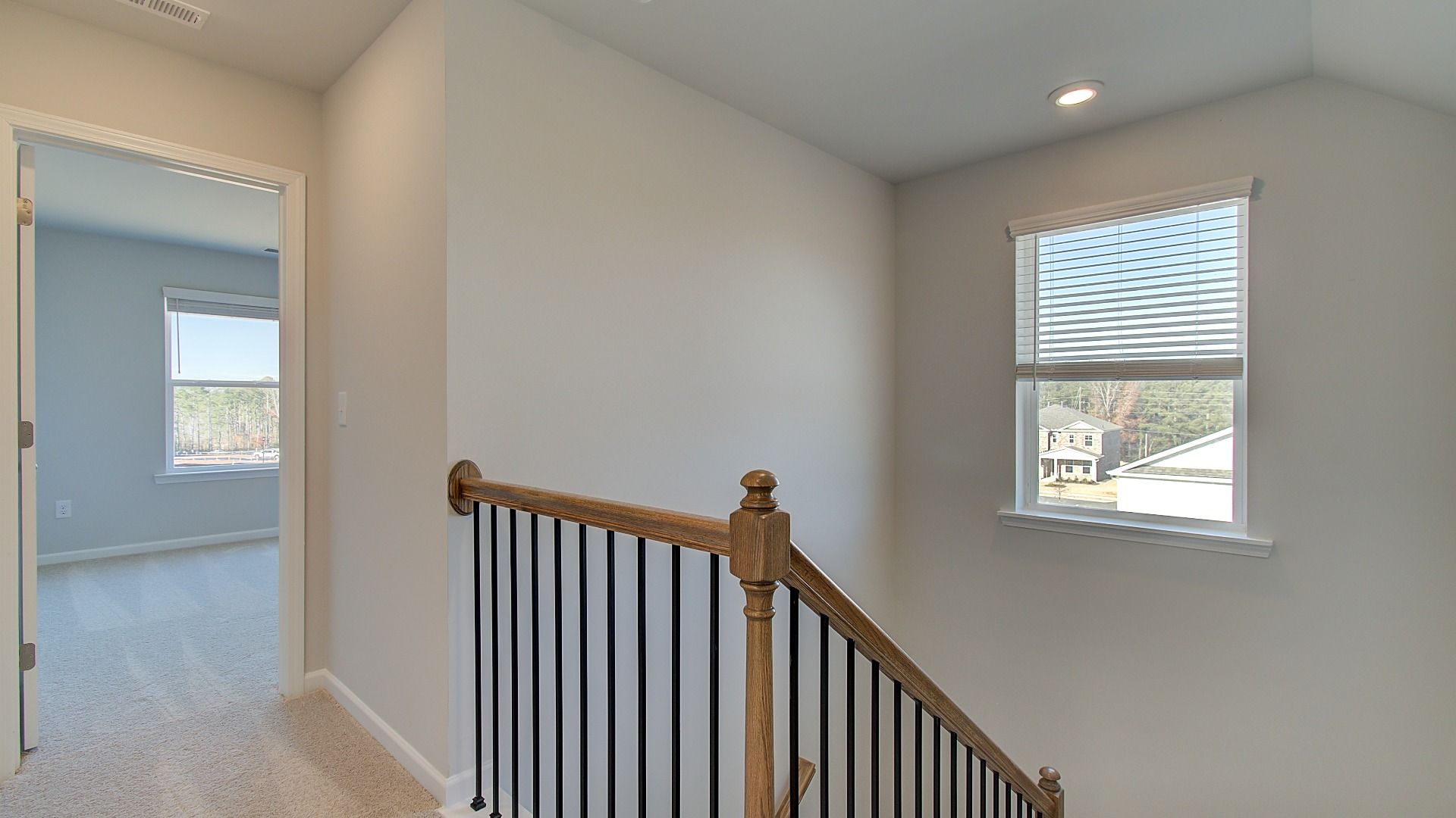 Pelham upstairs landing into open hallway with carpet flooring at Bowers Farm in McDonough, GA.