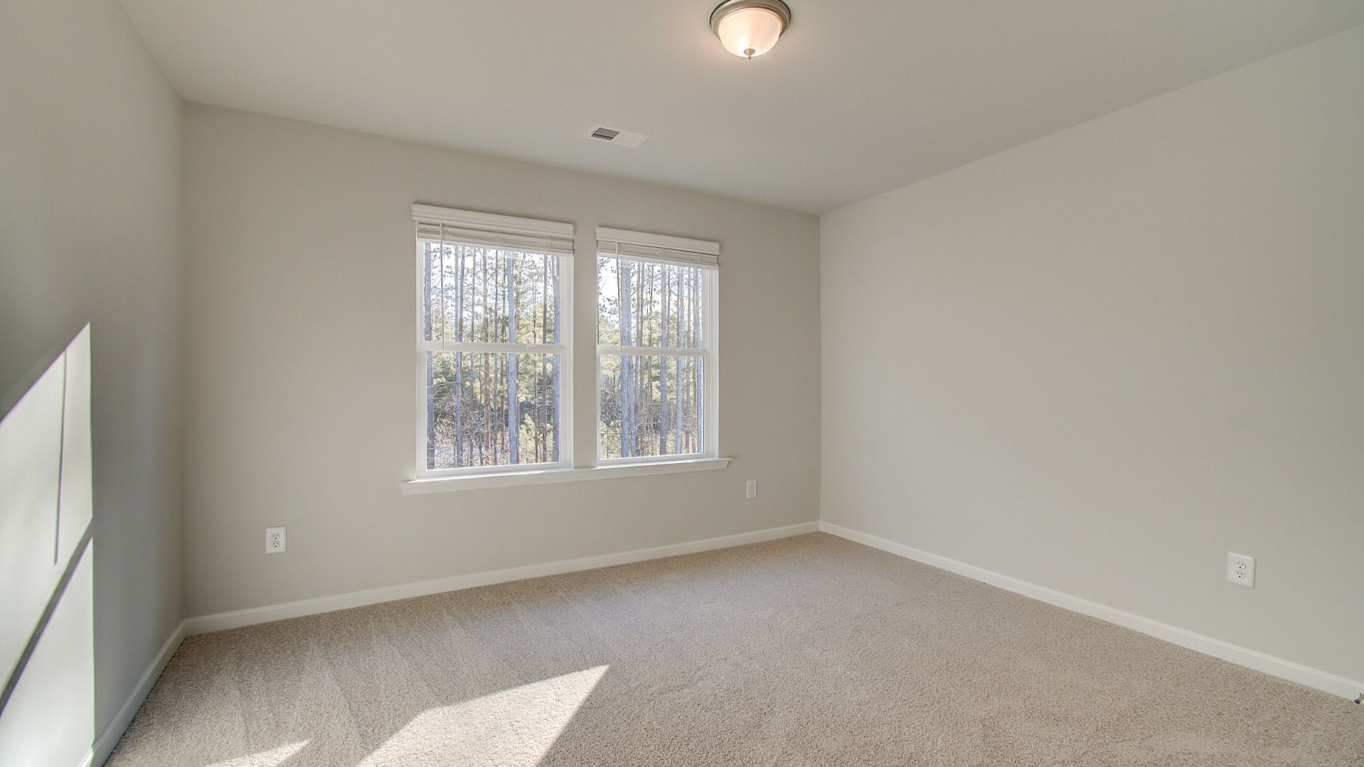 Secondary bedroom with generous space, natural light, and carpet flooring in the Pelham at Bowers Farm in McDonough, GA.