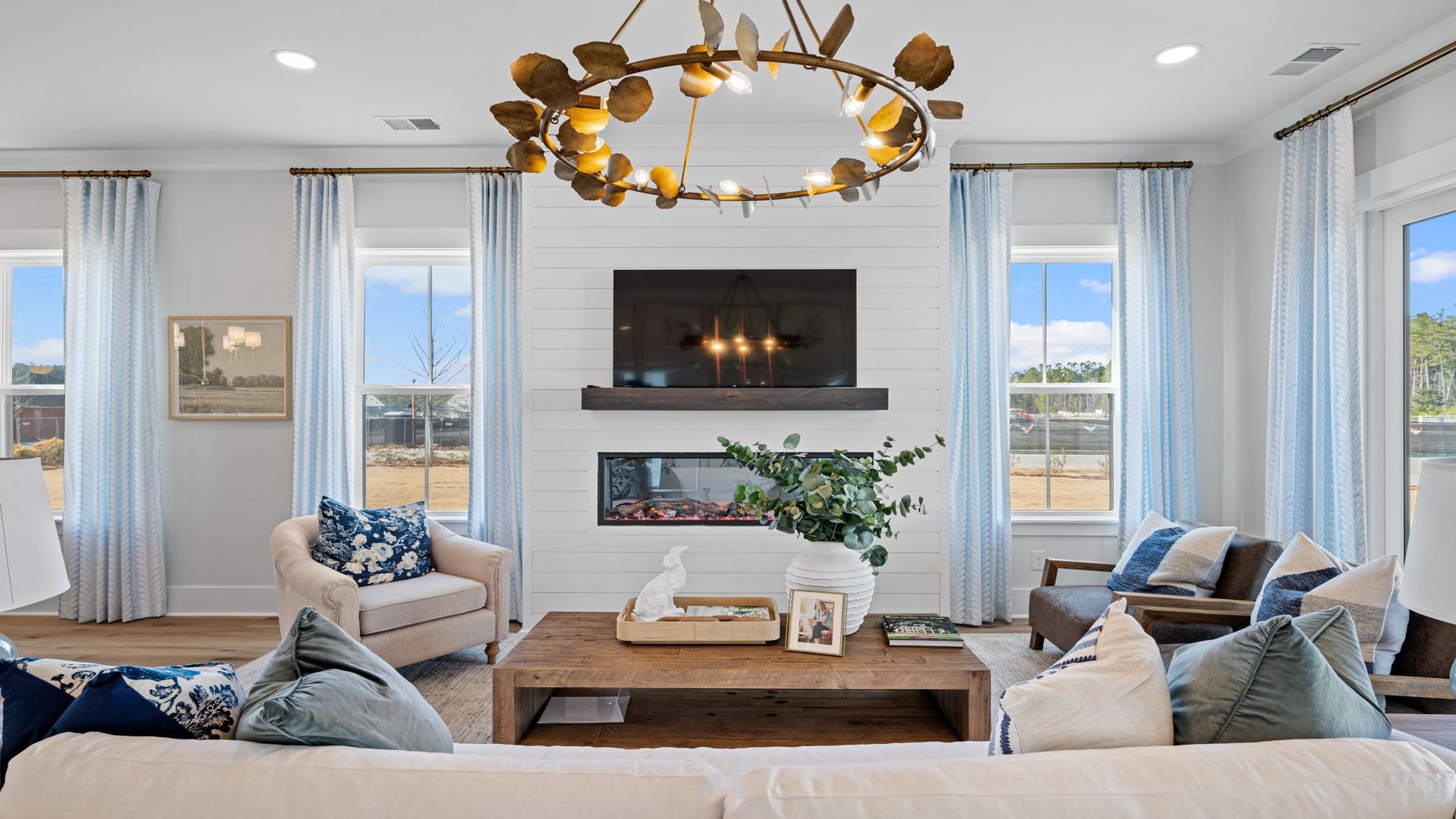 Living Room- Beaufain Model Home in Midtown at Nexton in by DRB homes offering an electric fireplace with lots of windows