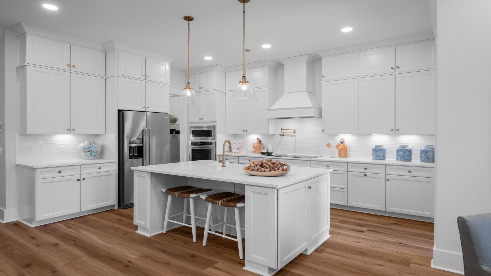 Kitchen- at Pamlico Terrace at by DRB Homes features an all-white kitchen island and gorgeous light fixtures