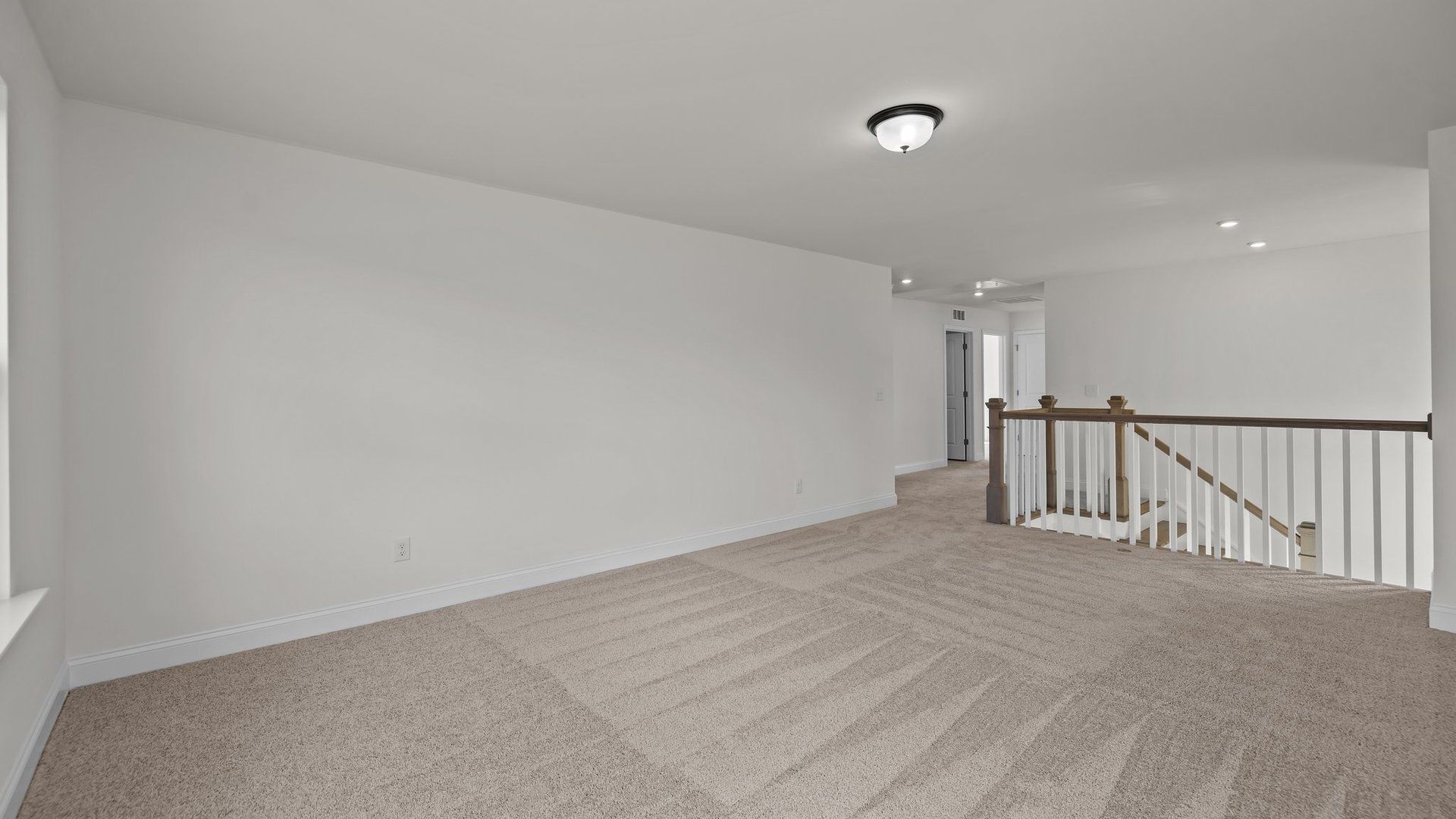 Spacious loft with plush carpeting, elevated ceiling and open rails, in the Norris Design by DRB Homes in York, SC