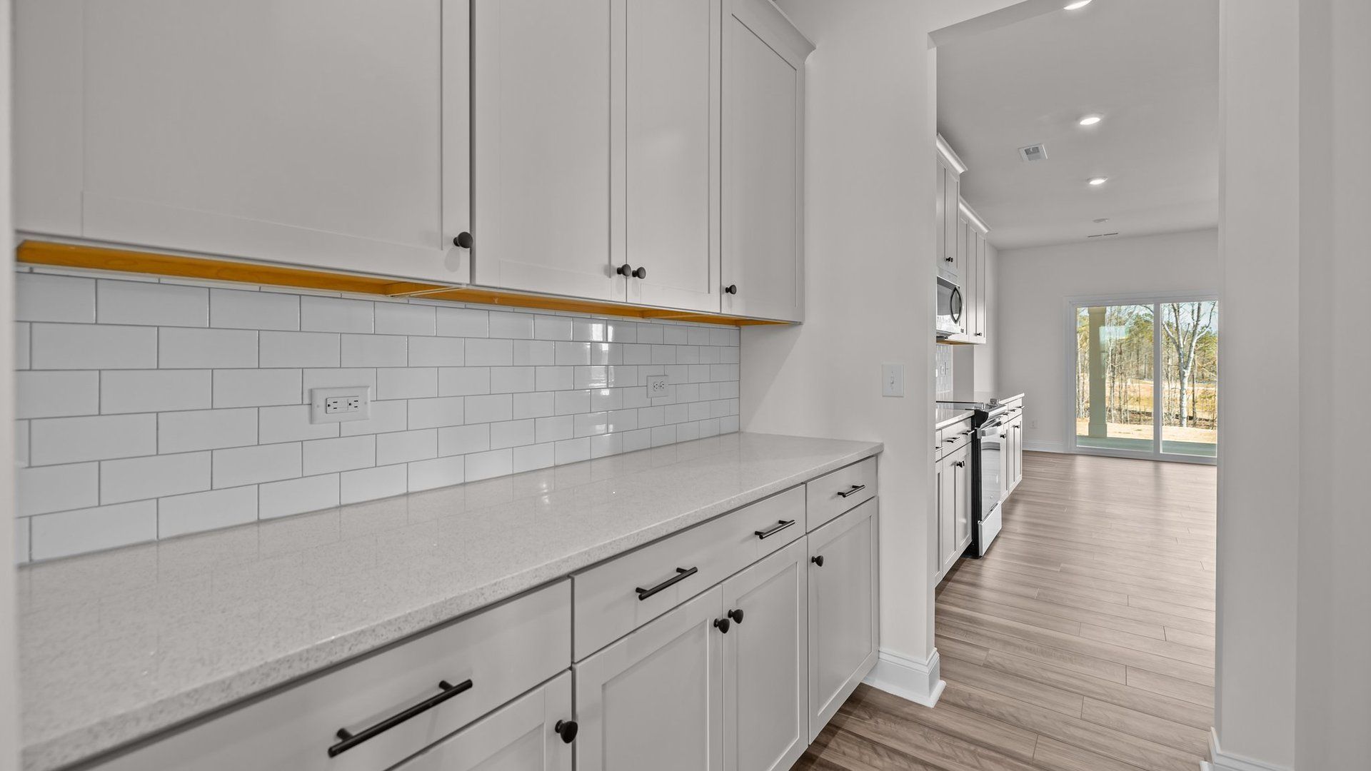 Elegant pass-through Butler's pantry with tile backsplash and premium cabinets, in the Norris Design by DRB Homes in York, SC