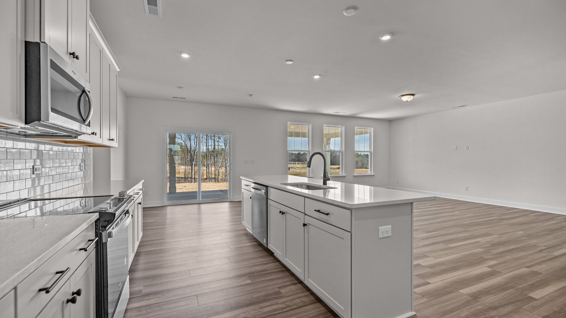 Open concept kitchen and family room with large windows and easy access to the covered porch; the Norris Design by DRB Homes