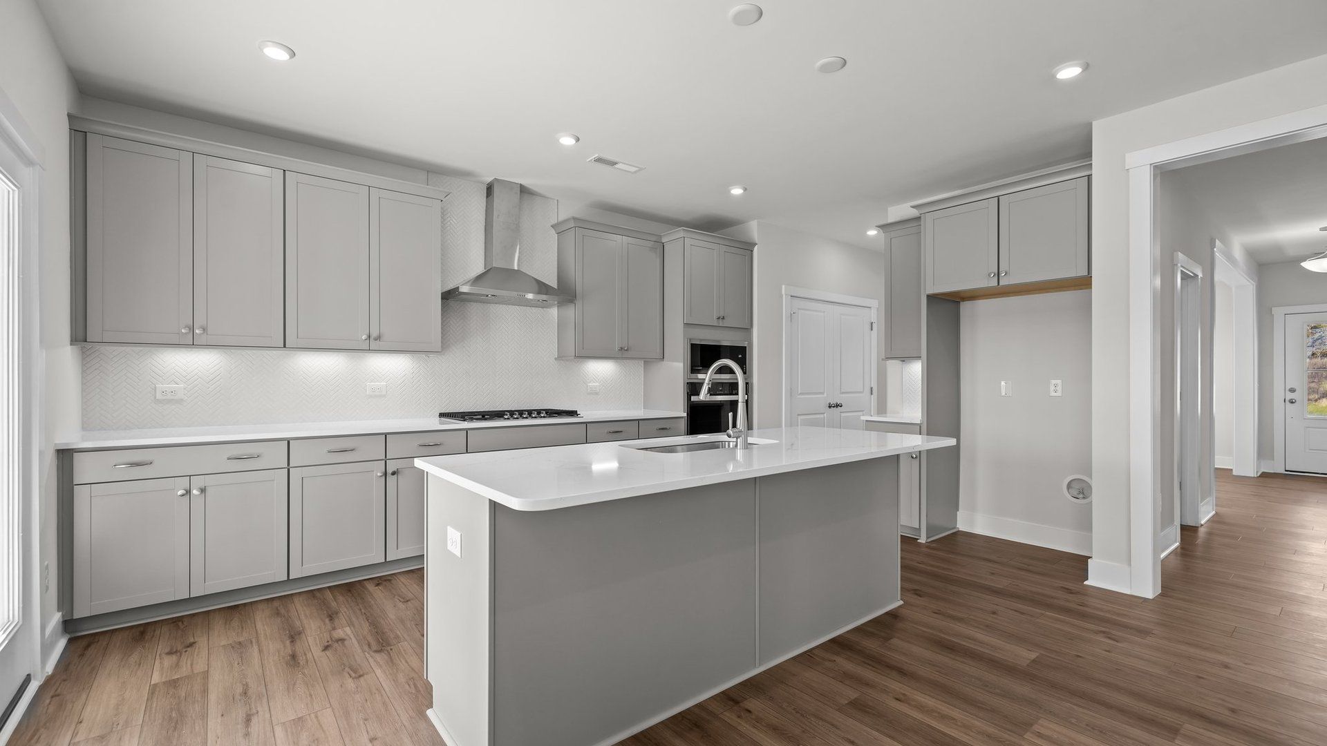 Burton Design gourmet kitchen with wall oven and microwave, vented hood, & cooktop. Lakeside Glen by DRB Homes in York, SC.