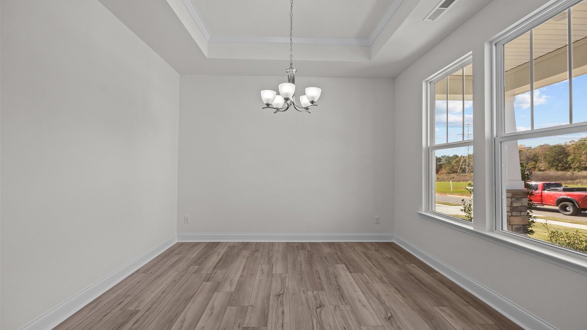Fairfield design well-lit dining area with raised tray ceiling and large windows. At Lakeside Glen by DRB Homes, York, SC.