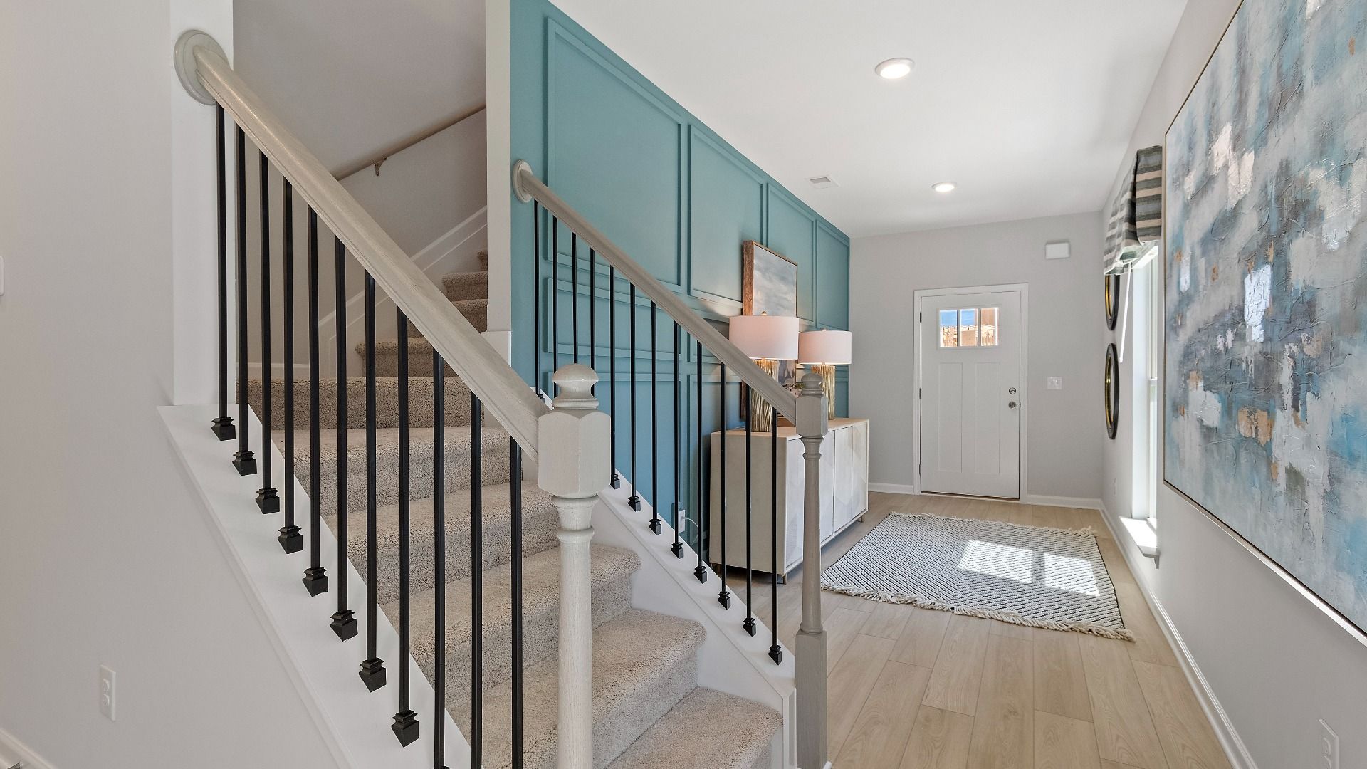 Reagan foyer featuring LVP flooring and modern staircase with black baluster at Abbotts Crossing in Conyers, GA.