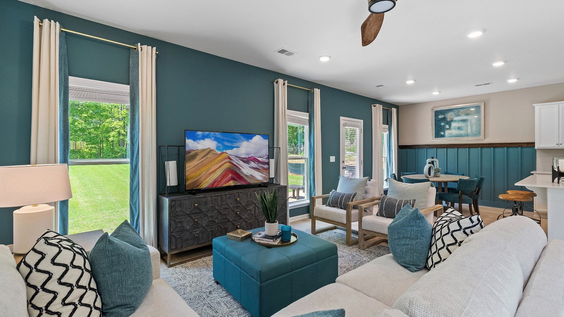 Spacious family room with modern design, ceiling fan and large windows at Abbotts Crossing in Conyers, GA.