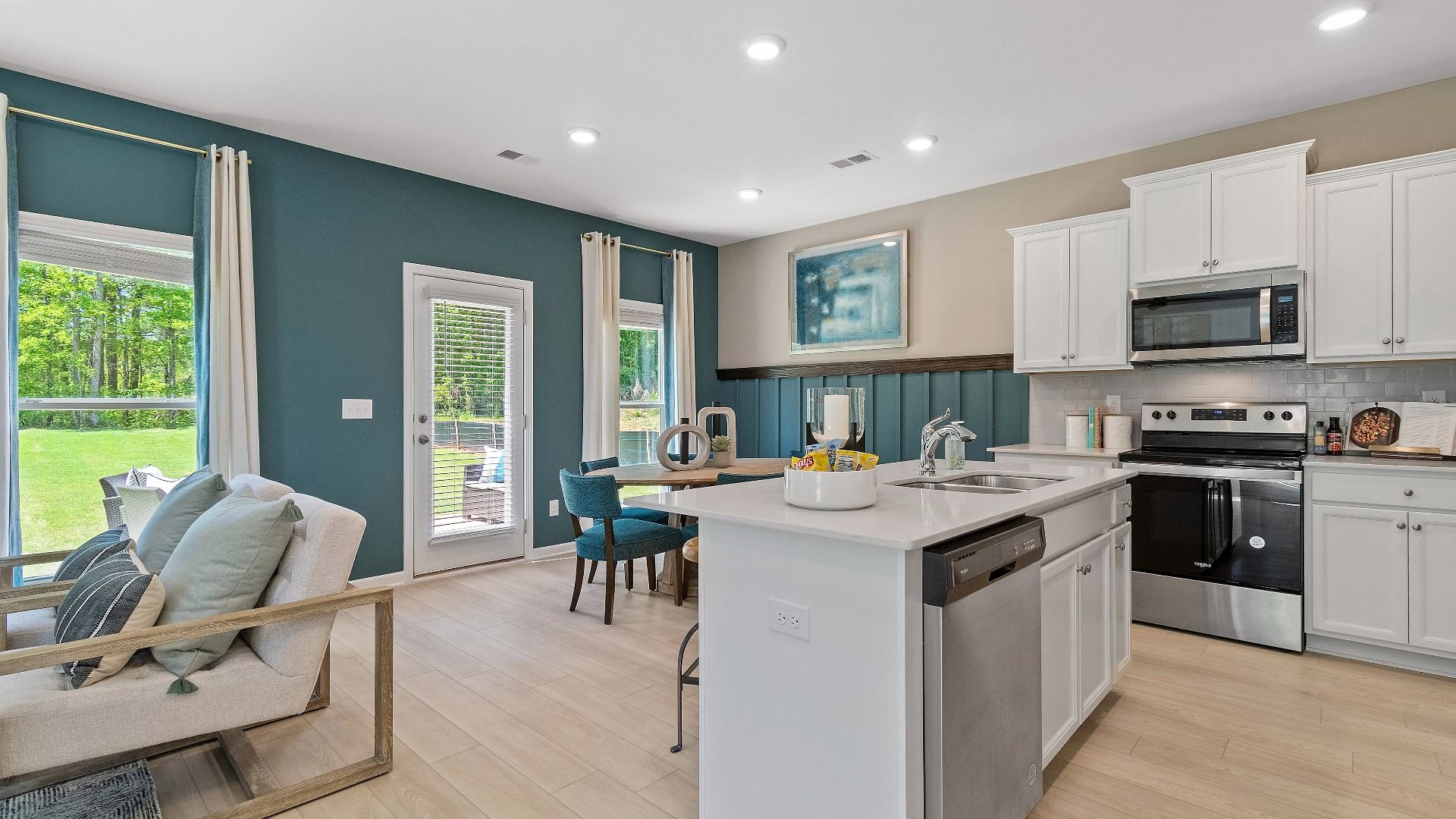 Reagan kitchen with bright, modern cabinetry and counters featuring stainless appliances and island at Abbotts Crossing.