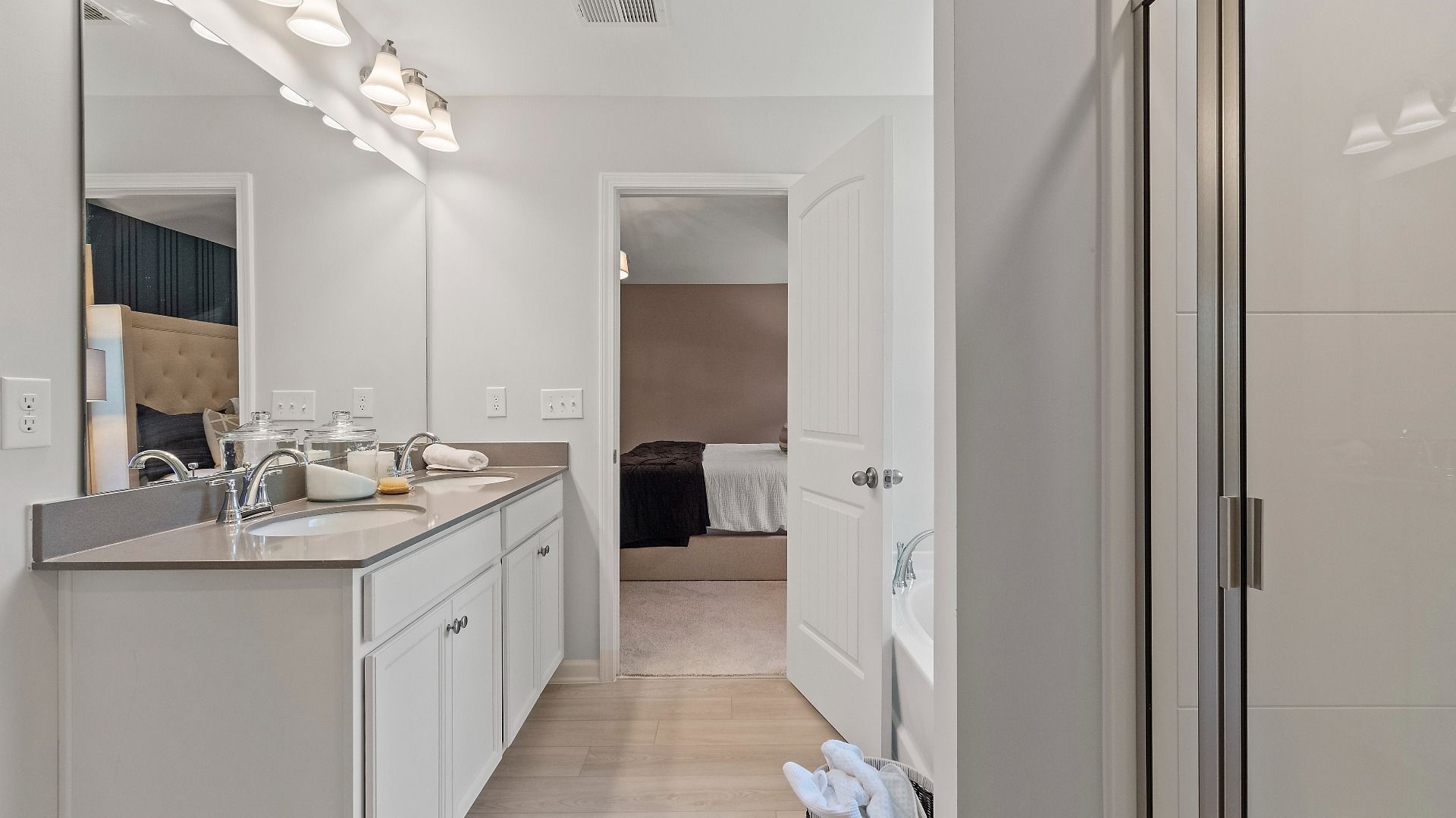 Primary suite bath featuring modern design, dual vanities and LVP flooring at Abbotts Crossing in Reagan floorplan.
