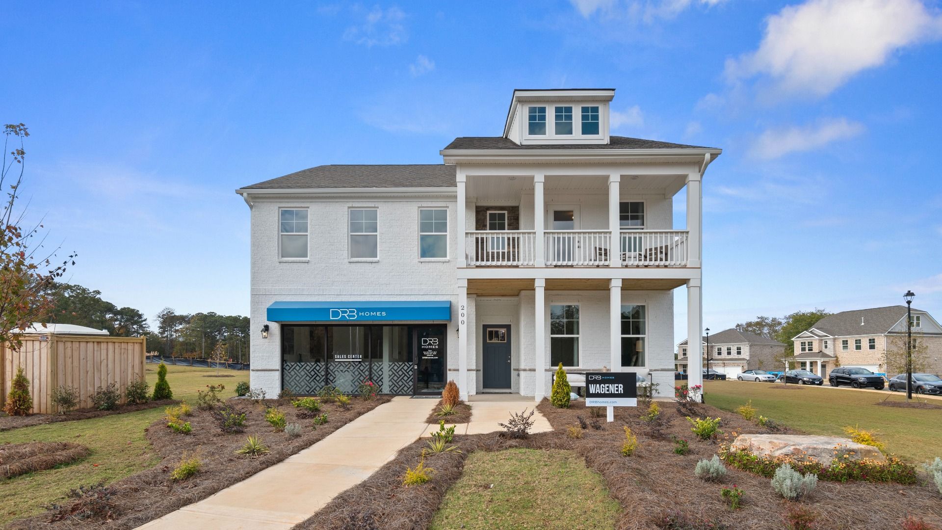 Wagener two-story single-family home with white brick exterior, balcony, and covered entry at Burchwood in Stockbridge, GA.