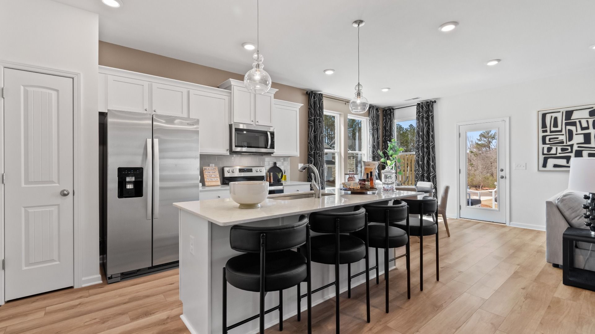 Austin Alternate open-concept kitchen with large island and modern gray tile backsplash at Bowers Farm Townhomes.
