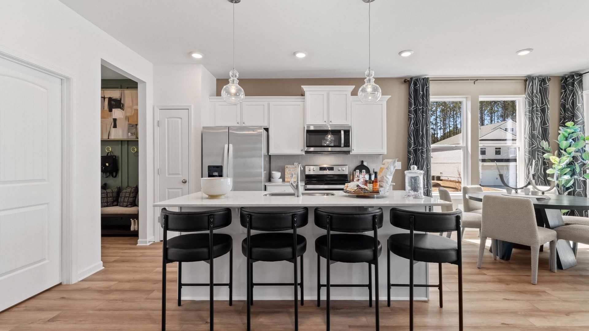 Austin Alternate open-concept kitchen with white cabinetry and large island with seating at Bowers Farm Townhomes.