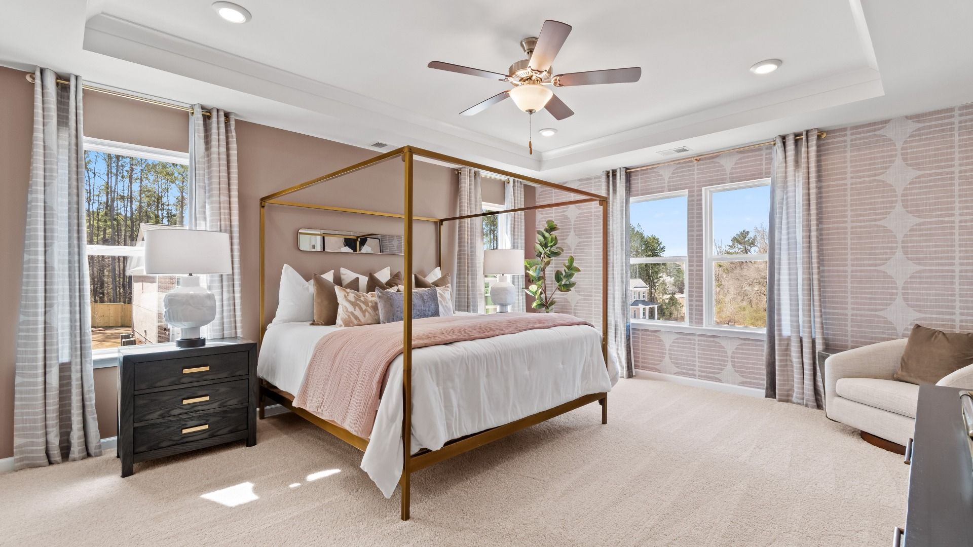 Spacious primary suite with tray ceiling, carpet flooring, and seating area in the Austin Alternate at Bowers Farm Townhomes.