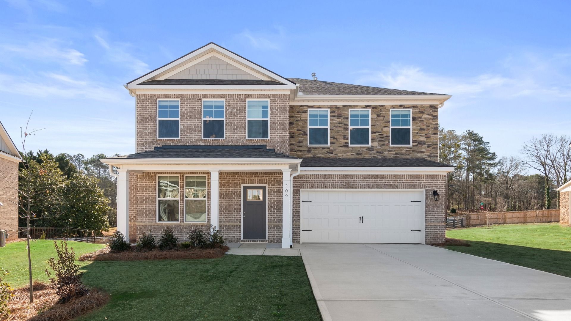 Ridgewood two-story home with brick-dominant exterior, stone accent, and two-car front-entry garage at Burchwood.