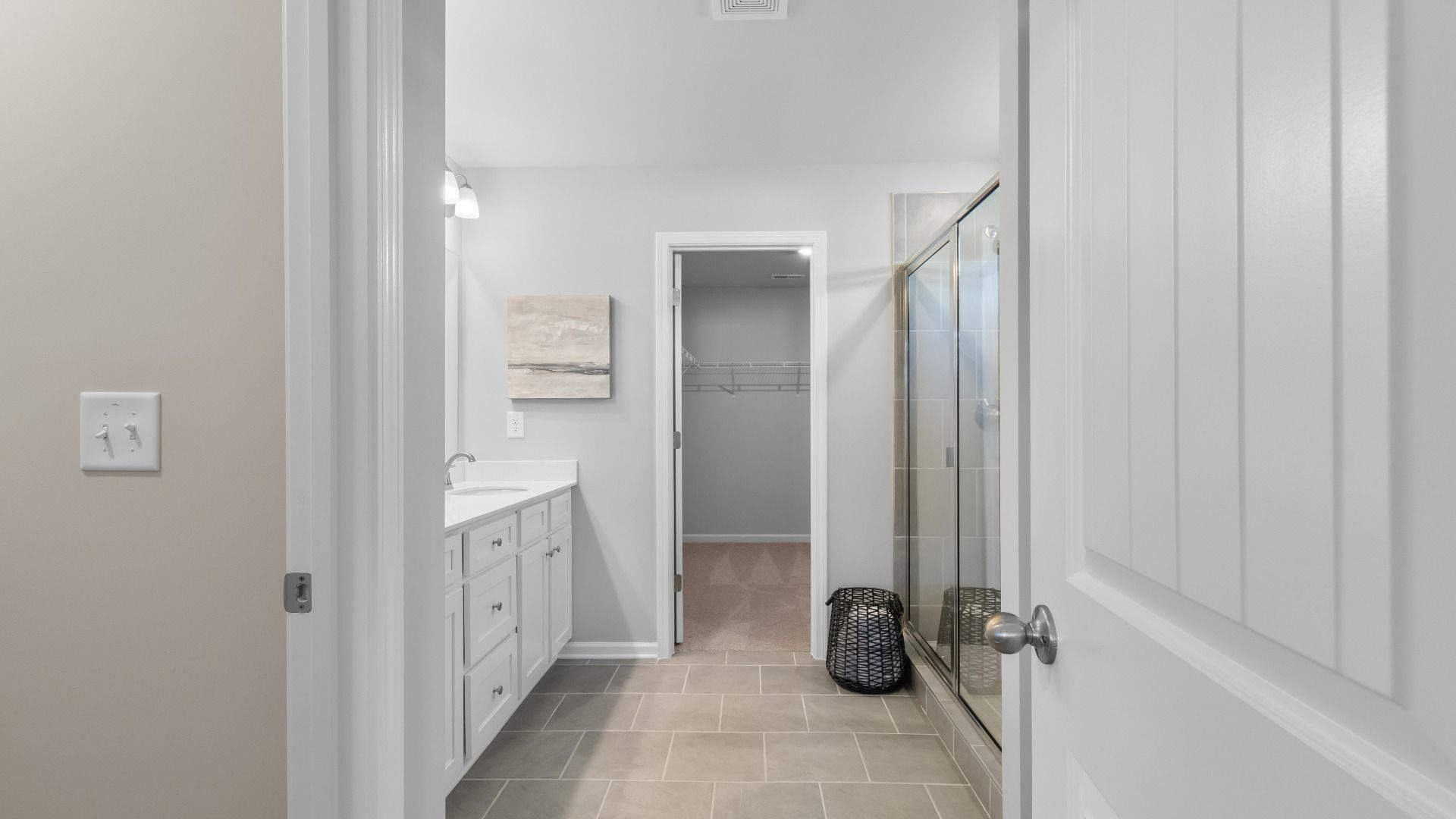 Primary bath with neutral tile flooring, dual vanities, and wak-in shower in the Ridgewood at Burchwood in Stockbridge, GA.