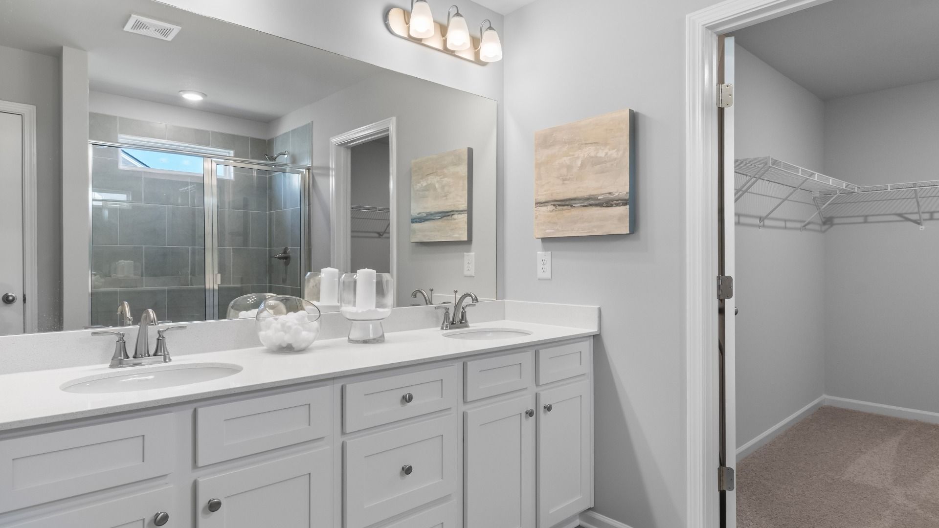 Ridgewood primary bath with dual vanities, walk-in shower, and connected walk-in closet at Burchwood in Stockbridge, GA.