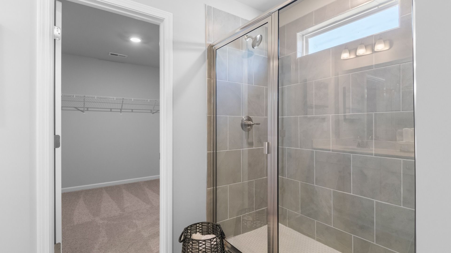 Ridgewood primary bath with tile-wall walk-in shower and connected walk-in closet at Burchwood in Stockbridge, GA.
