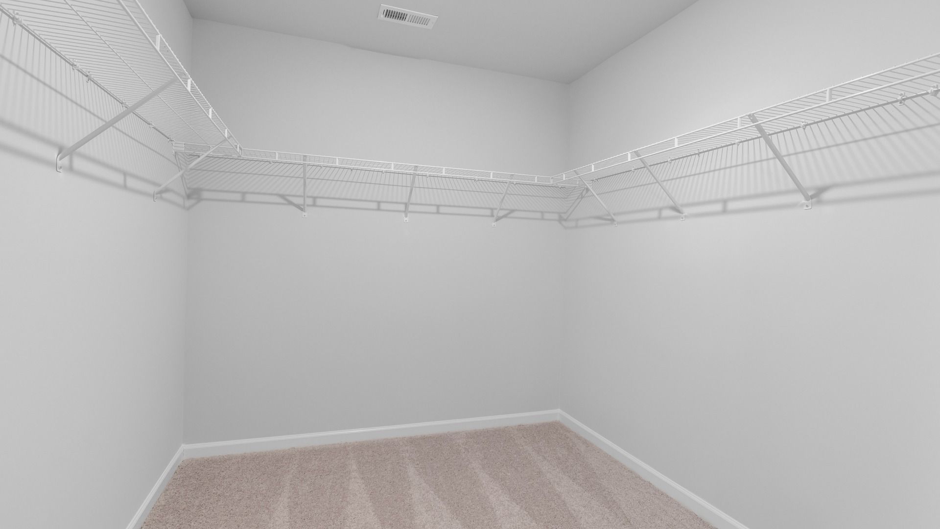 Ridgewood primary walk-in closet with built-in shelving and carpet flooring at Burchwood in Stockbridge, GA.
