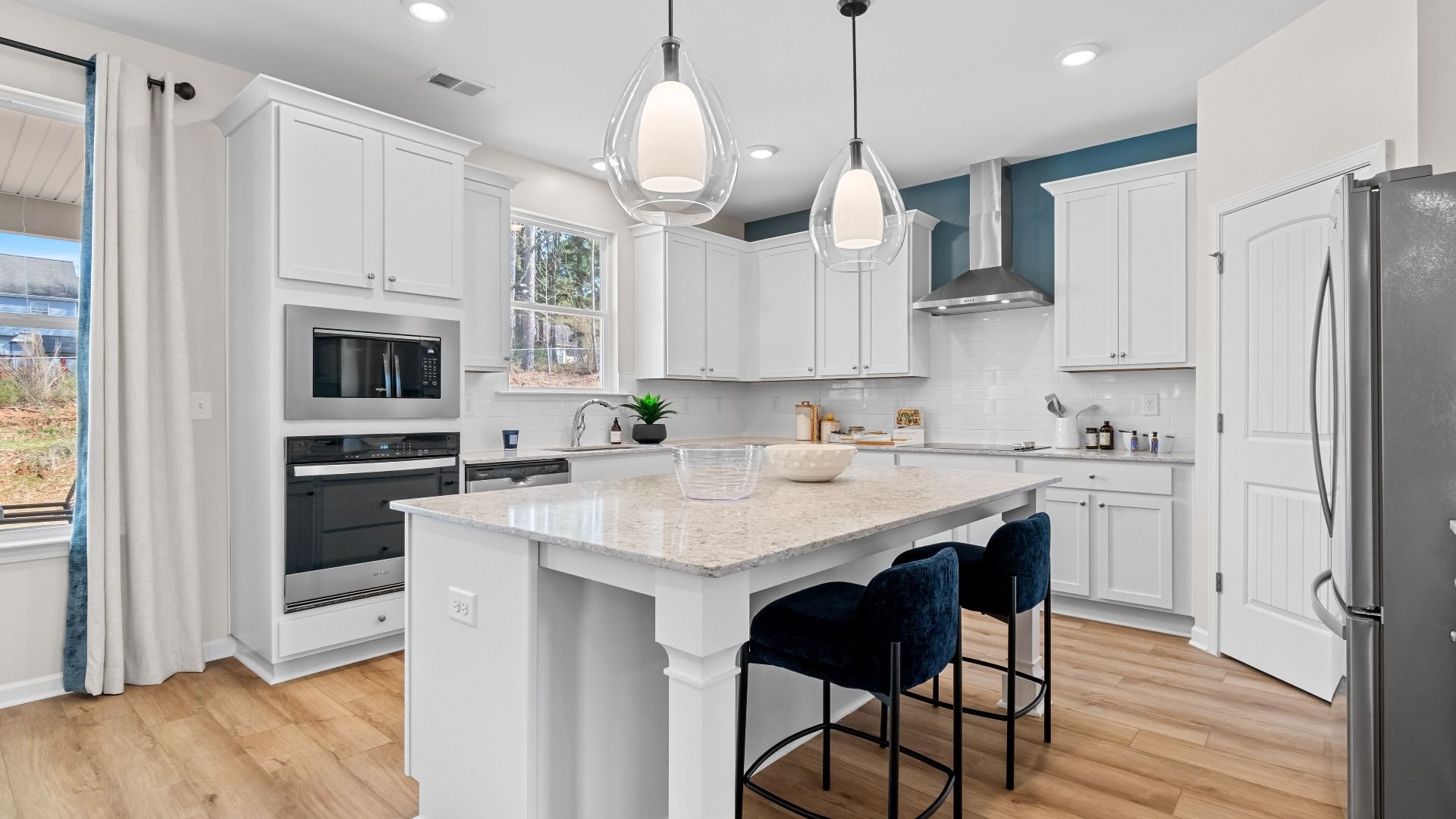 Bright modern Wynwood kitchen with pendant lighting, white cabinetry, and center island with seating at Bowers Farm.