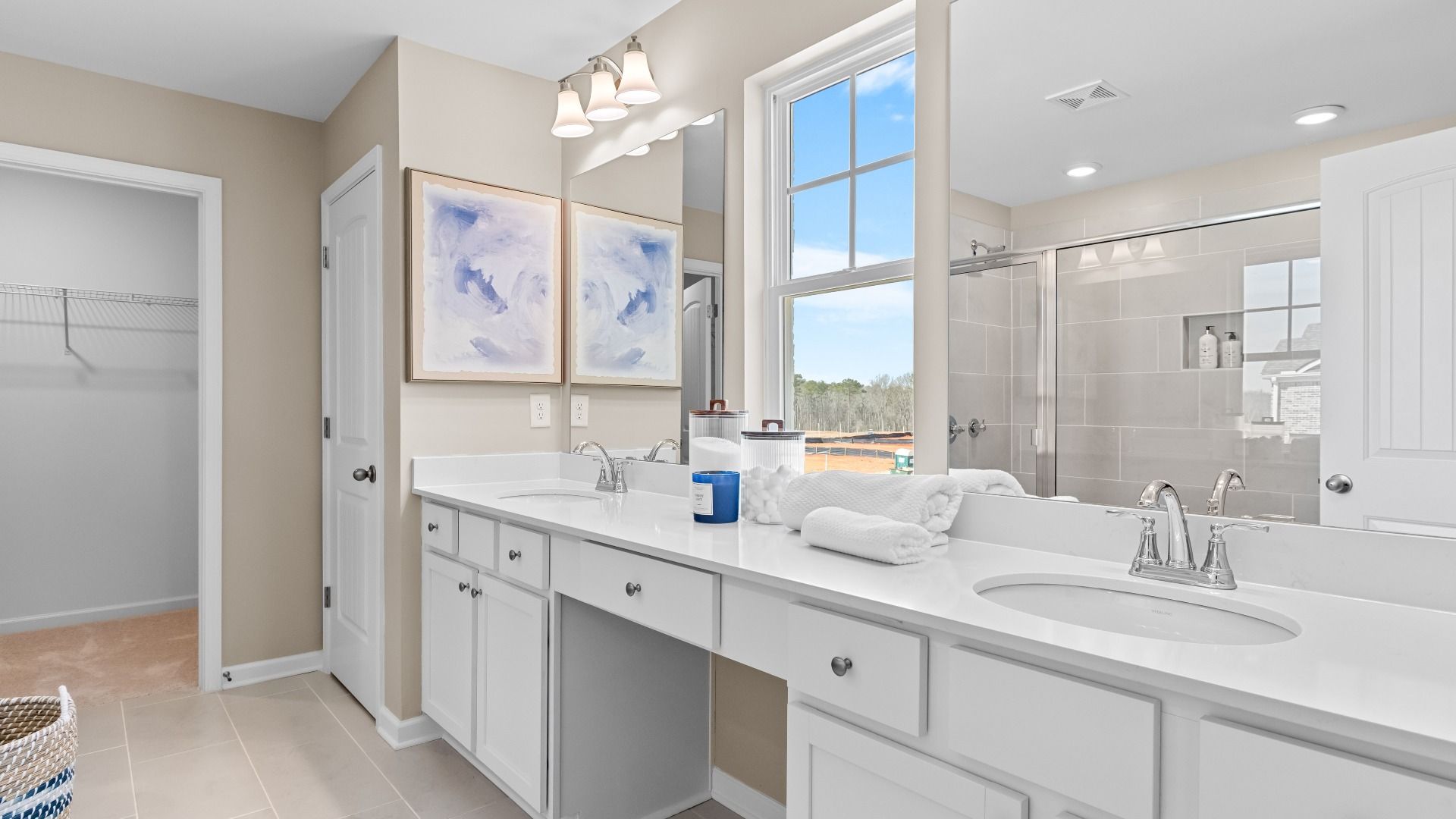 Bright primary bath with dual vanities, tile floors, and white modern design in the Wynwood at Bowers Farm in McDonough, GA.