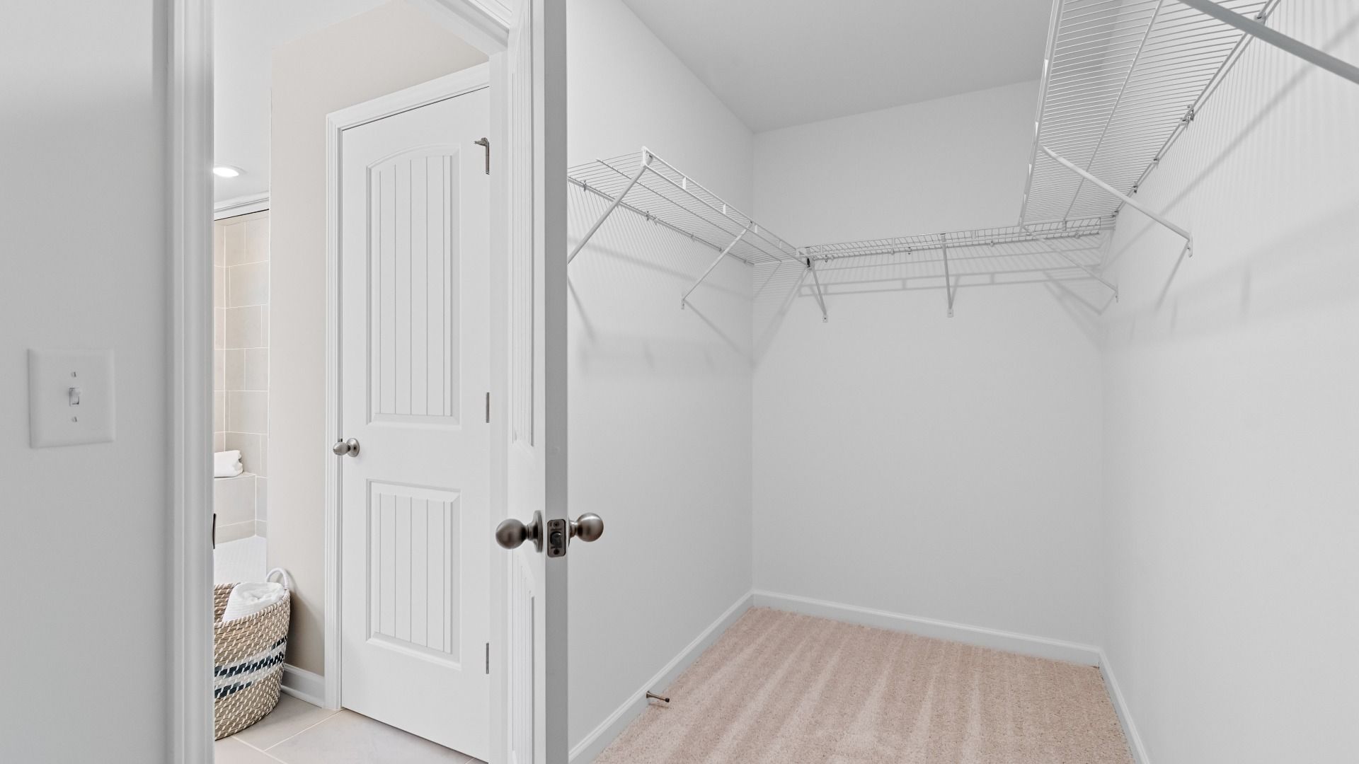 Generously sized Wynwood primary closet with carpet flooring, built-in shelves, and railings at Bowers Farm in McDonough, GA.