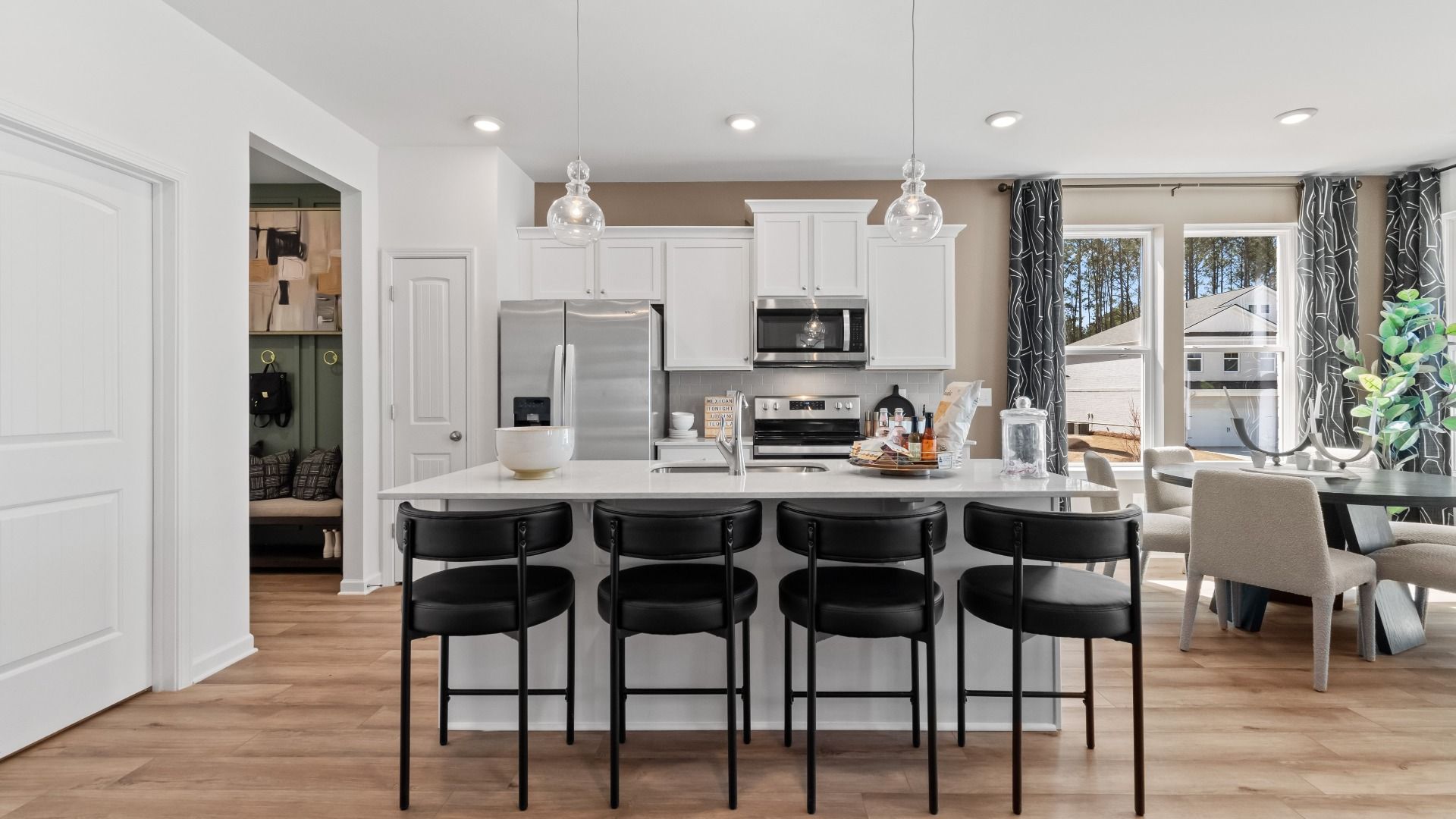 Kitchen with white cabinetry, large island, stainless steel appliances, and open dining area at Bowers Farm in McDonough, GA.