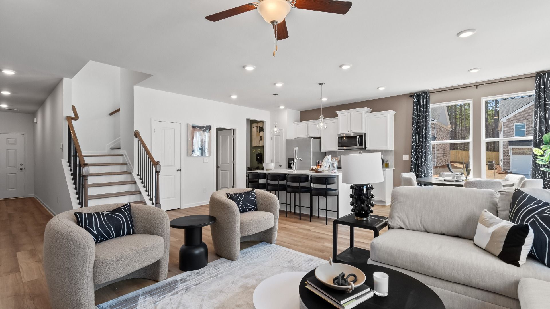 Spacious, bright family room at Bowers Farm with layout flowing into kitchen, breakfast area, and staircase in McDonough, GA.