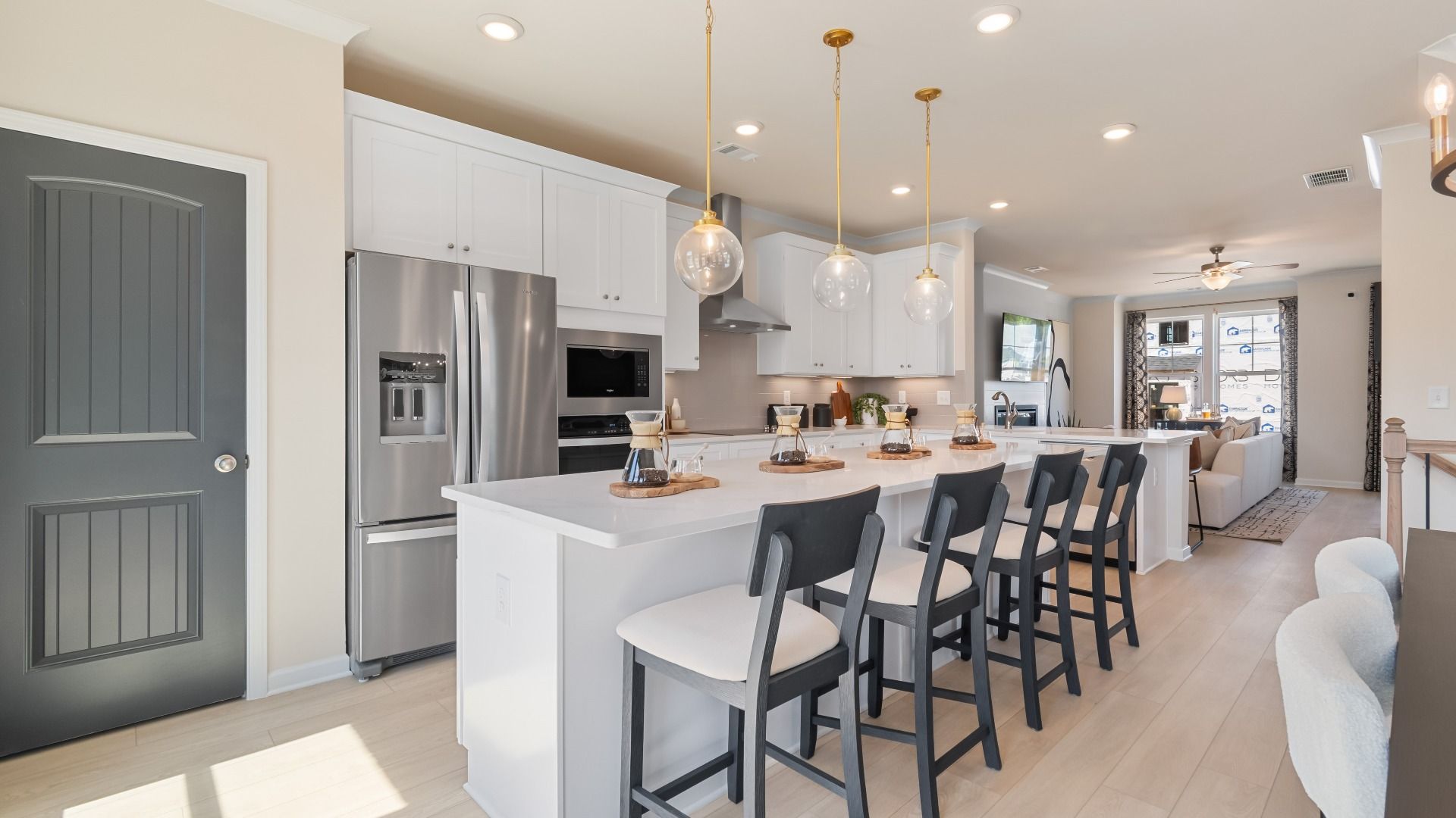 Modern kitchen featuring expansive island, white cabinetry, and pendant lighting in new construction townhome at Silverock.