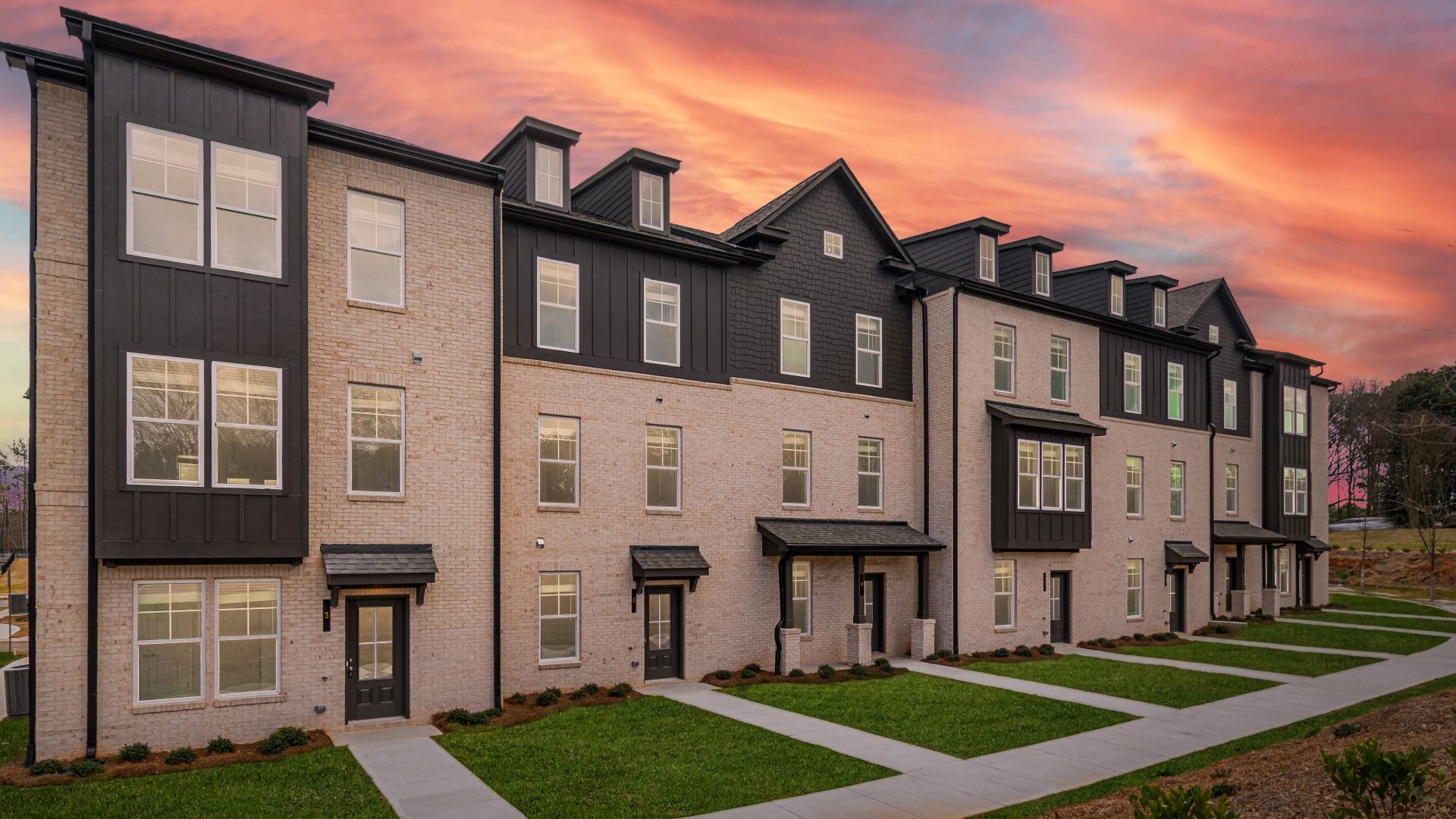 Front exterior of a modern townhome with light brick and dark siding accents at Silverock in McDonough, GA.