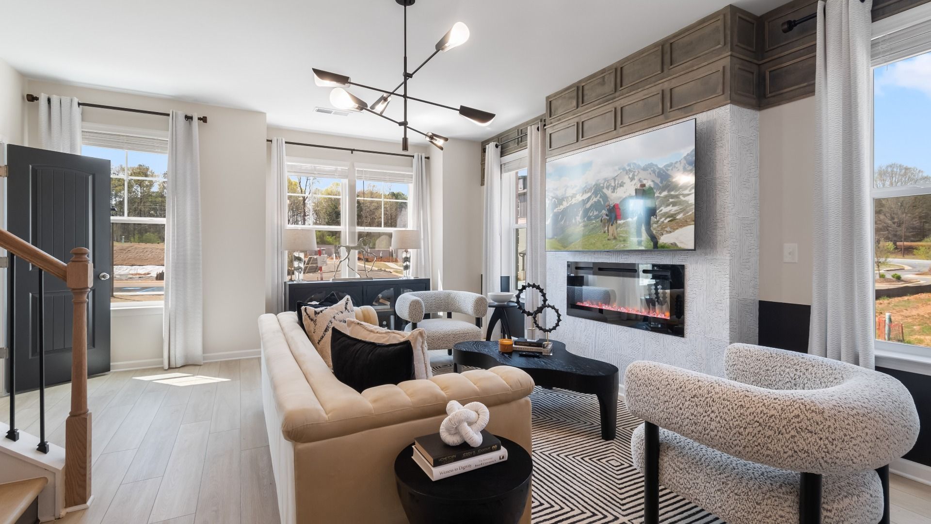 Bright open living space with electric fireplace, modern accent details, and expansive windows at Daybreak in Newnan, GA.