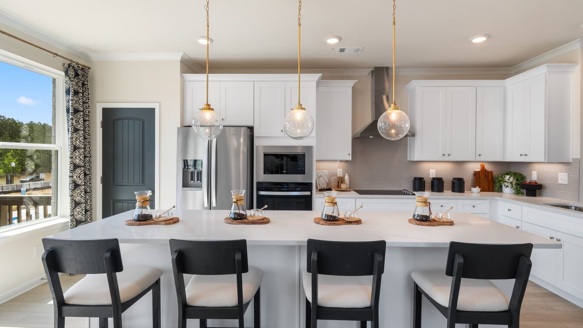 Bright kitchen with white cabinetry, stainless steel appliances, and a large island at Silverock in McDonough, GA.