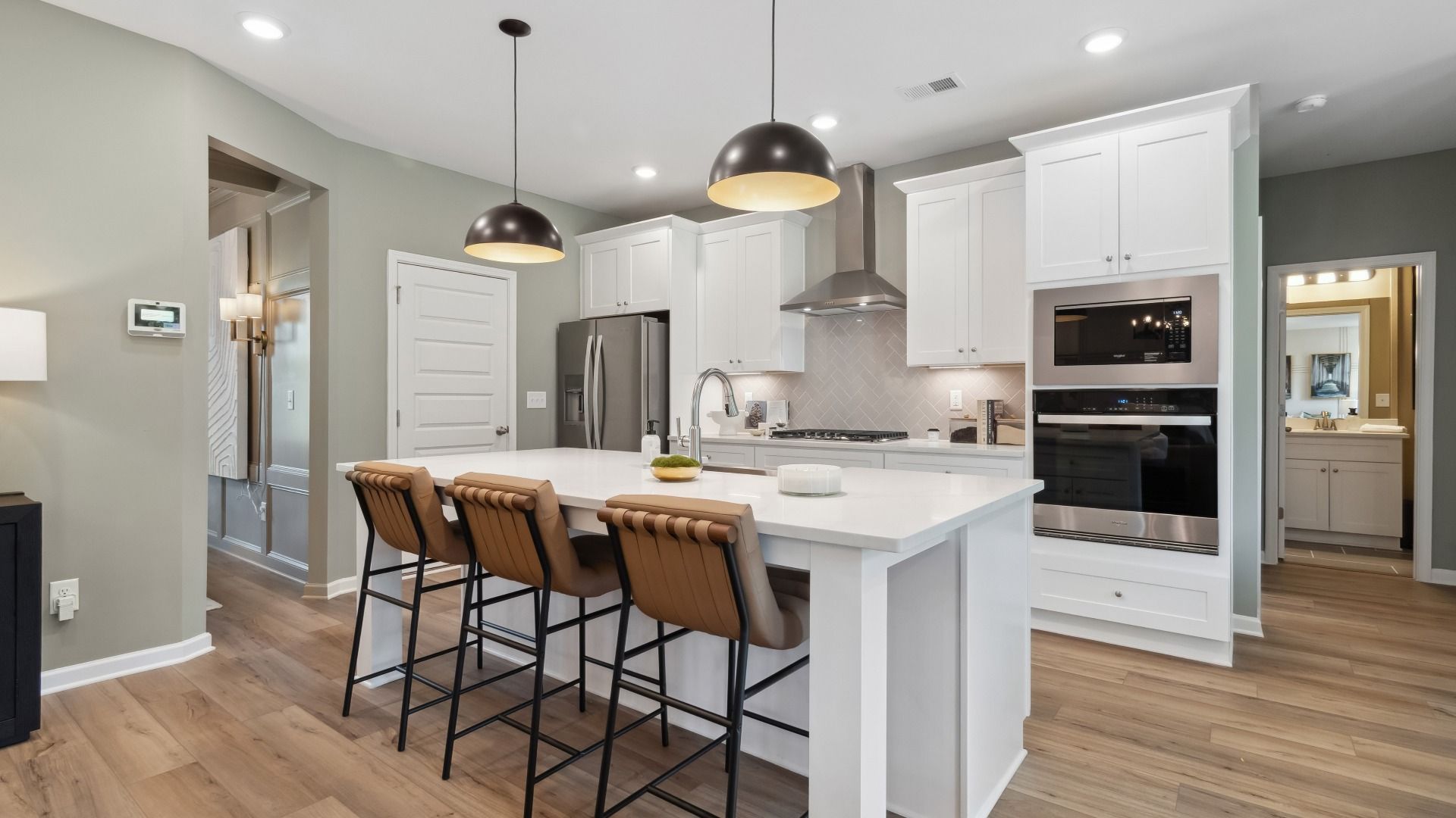 Modern kitchen featuring island seating, pendant lighting, and white cabinetry at Westwind Estates in Hampton, GA.