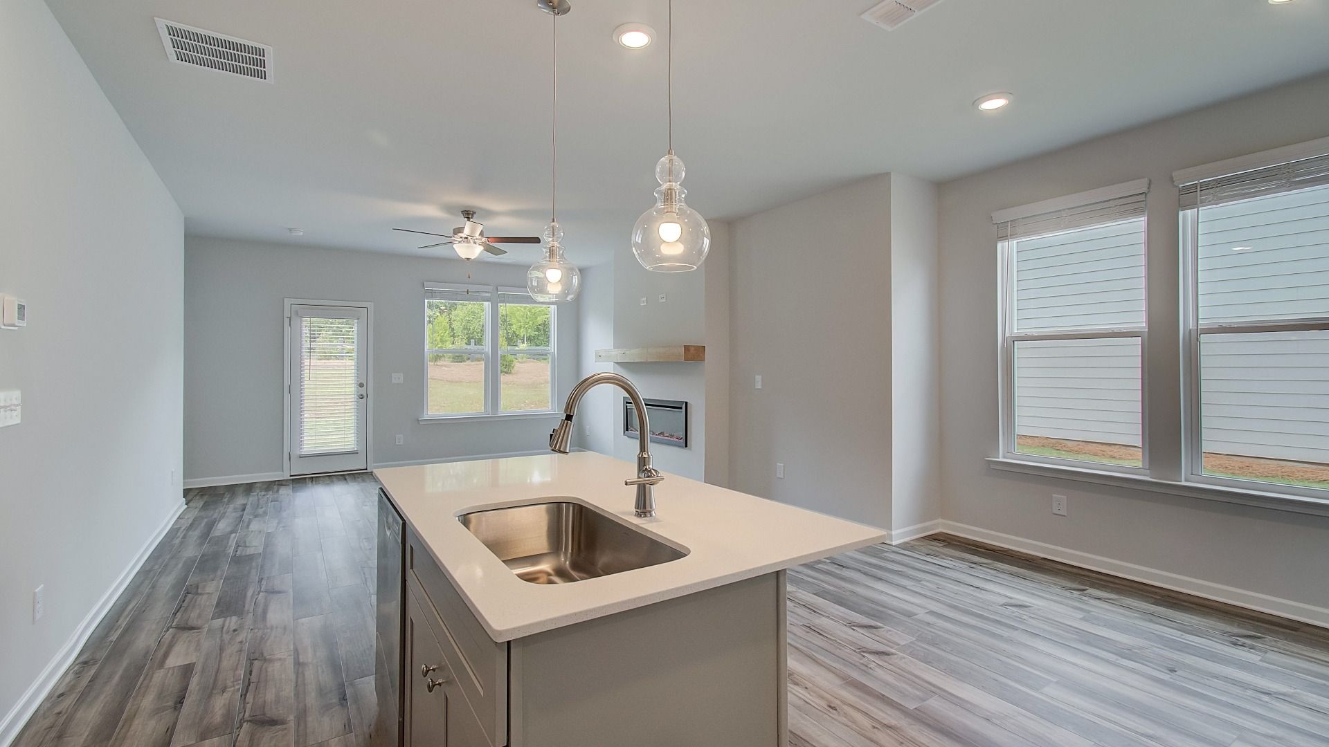 Bright open kitchen featuring center island, grey cabinets, quartz counters, and stainless steel range and microwave.
