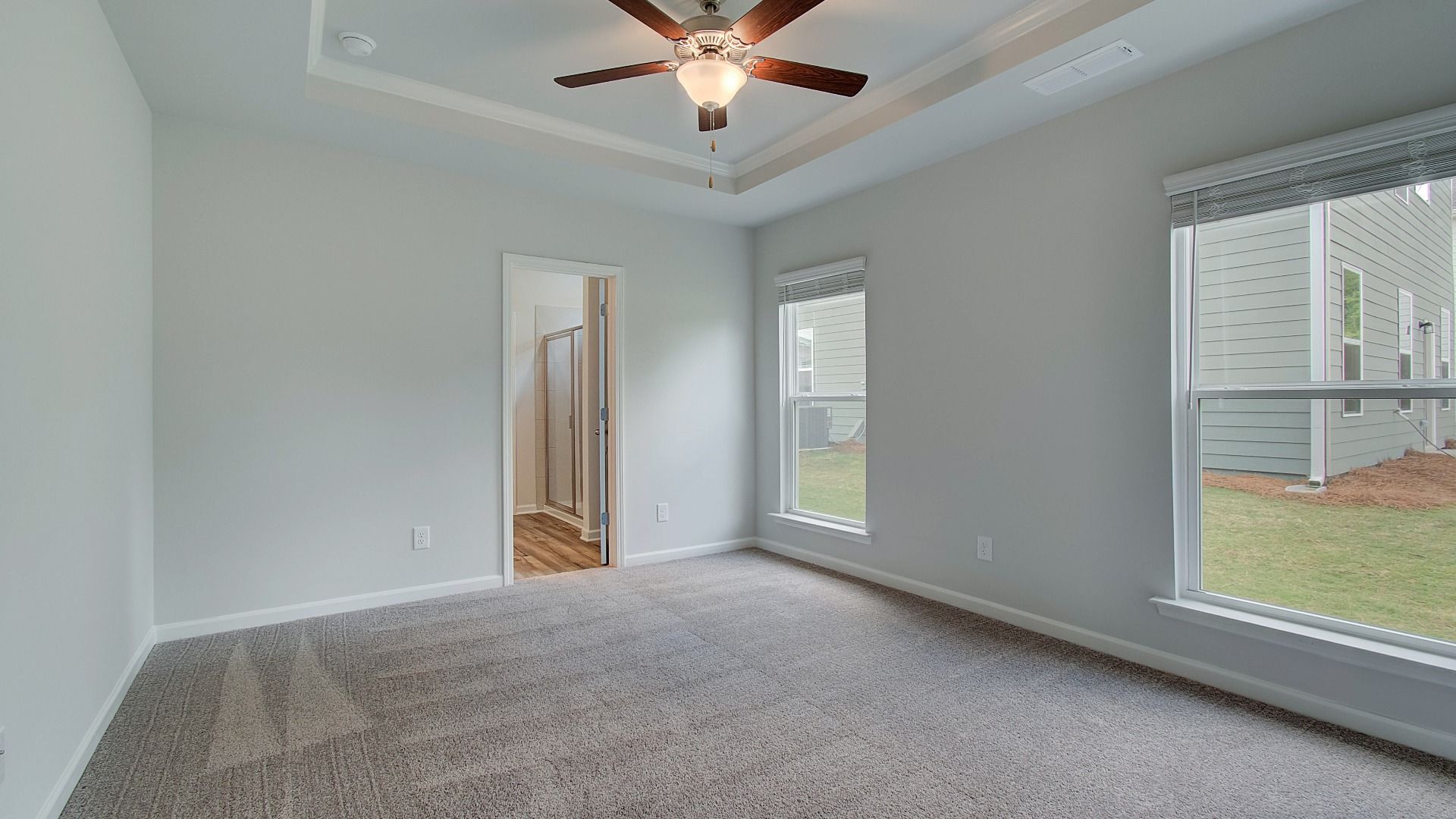 Spacious primary suite with elegant tray ceiling, large windows, and abundant natural light.