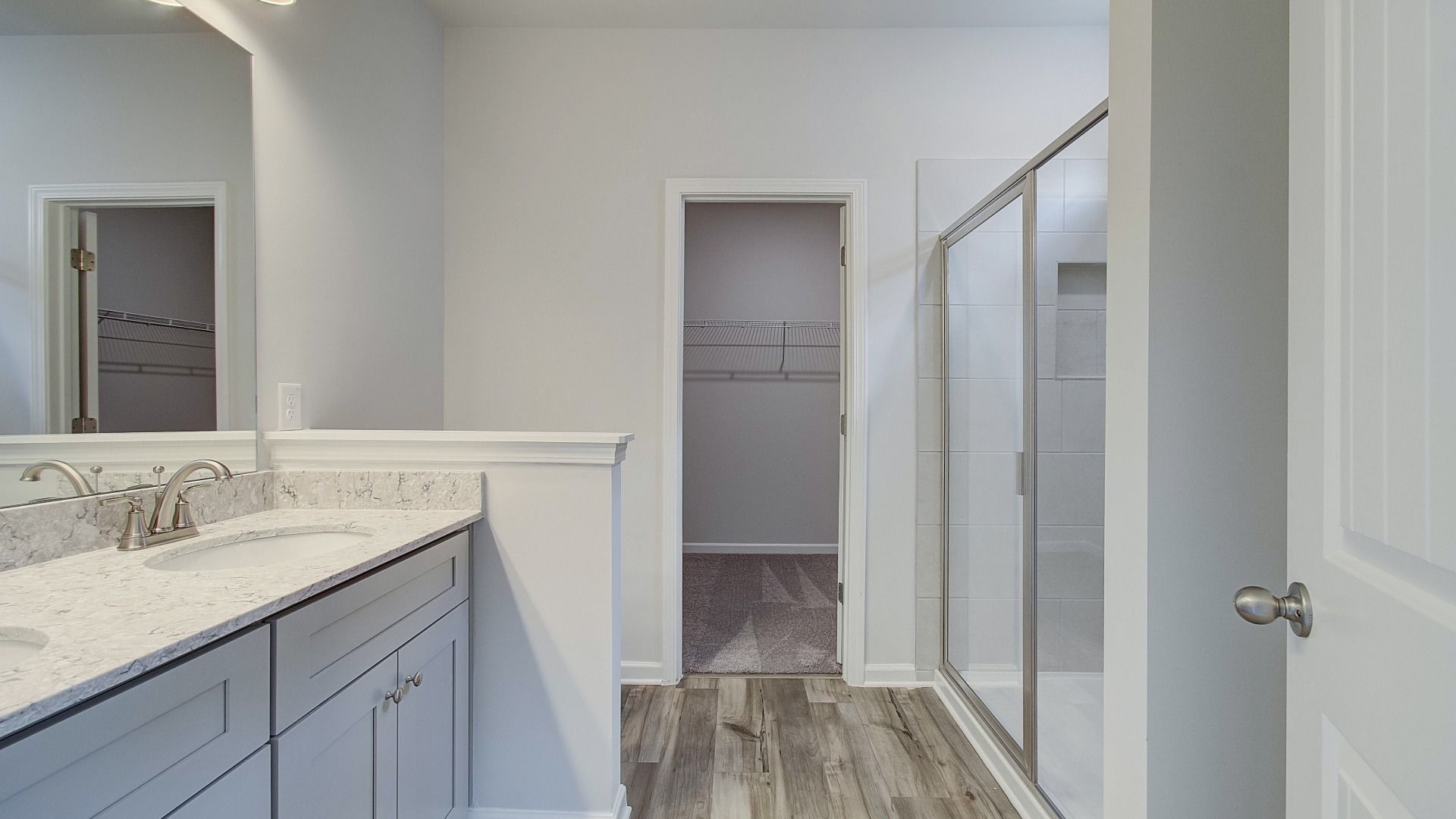 Luxurious primary bathroom with double vanities, quartz countertops, and separate walk-in shower.