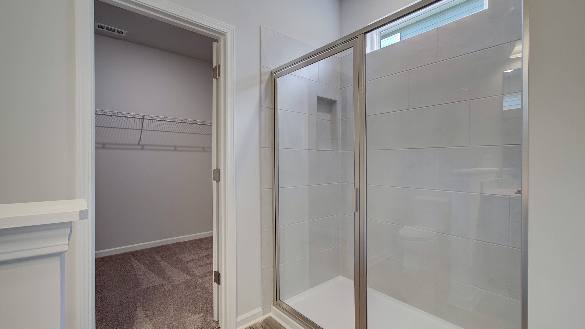 Modern tiled shower with glass door, built-in niche, sleek hardware and built-in bench.