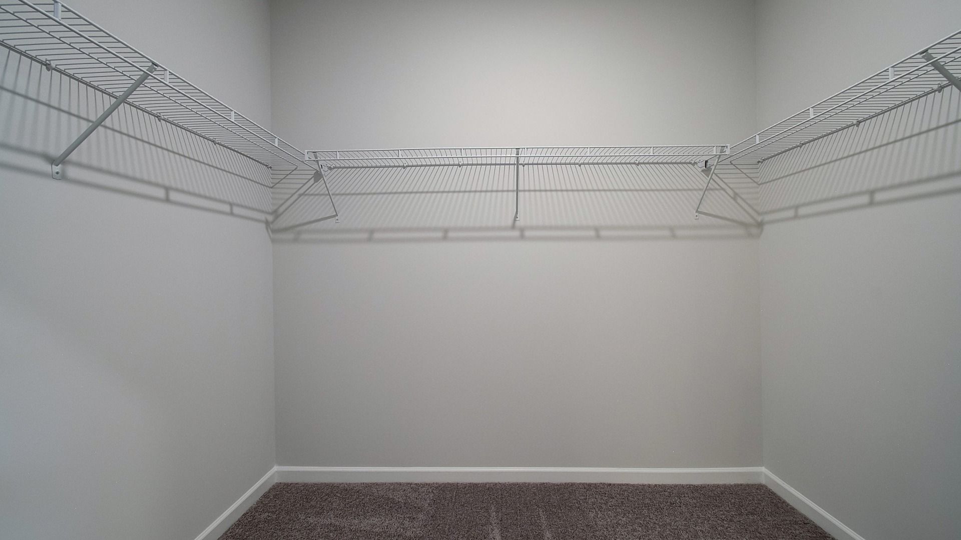 Large walk-in closet featuring generous shelving, rods, and storage space for clothing and shoes.