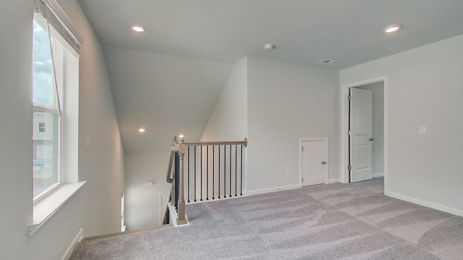 Open second-floor landing with rail overlook, neutral palette, and abundant light in new construction townhome.