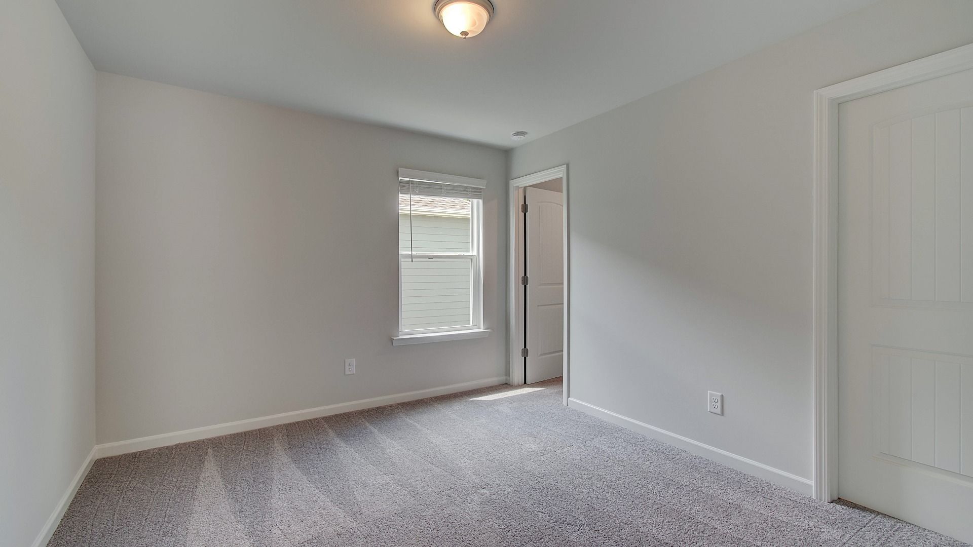 Spacious bedroom or office space featuring and abundant natural light from large window in new construction home.