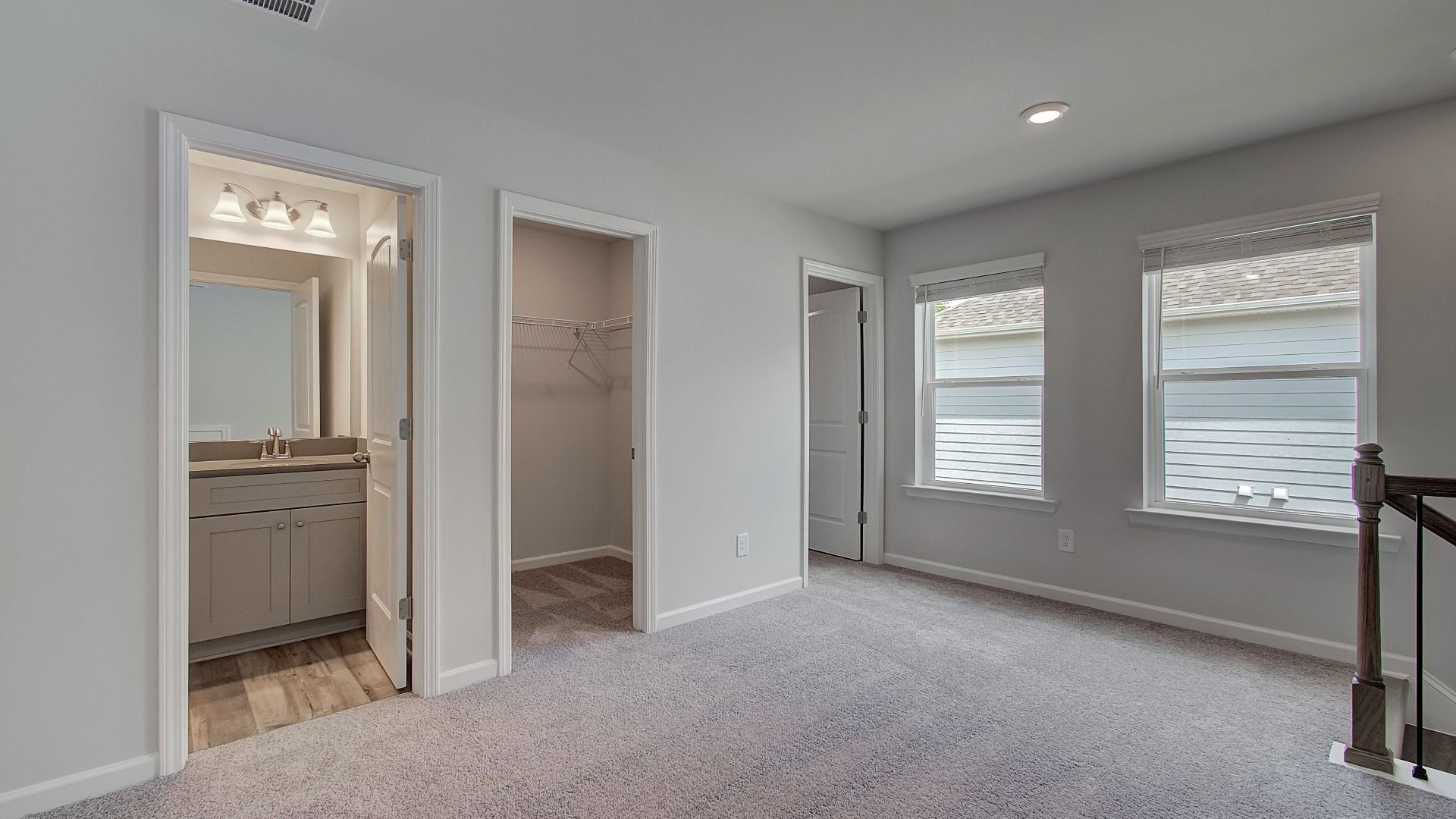 Open second-floor landing with rail overlook, neutral palette, and abundant light in new construction townhome.
