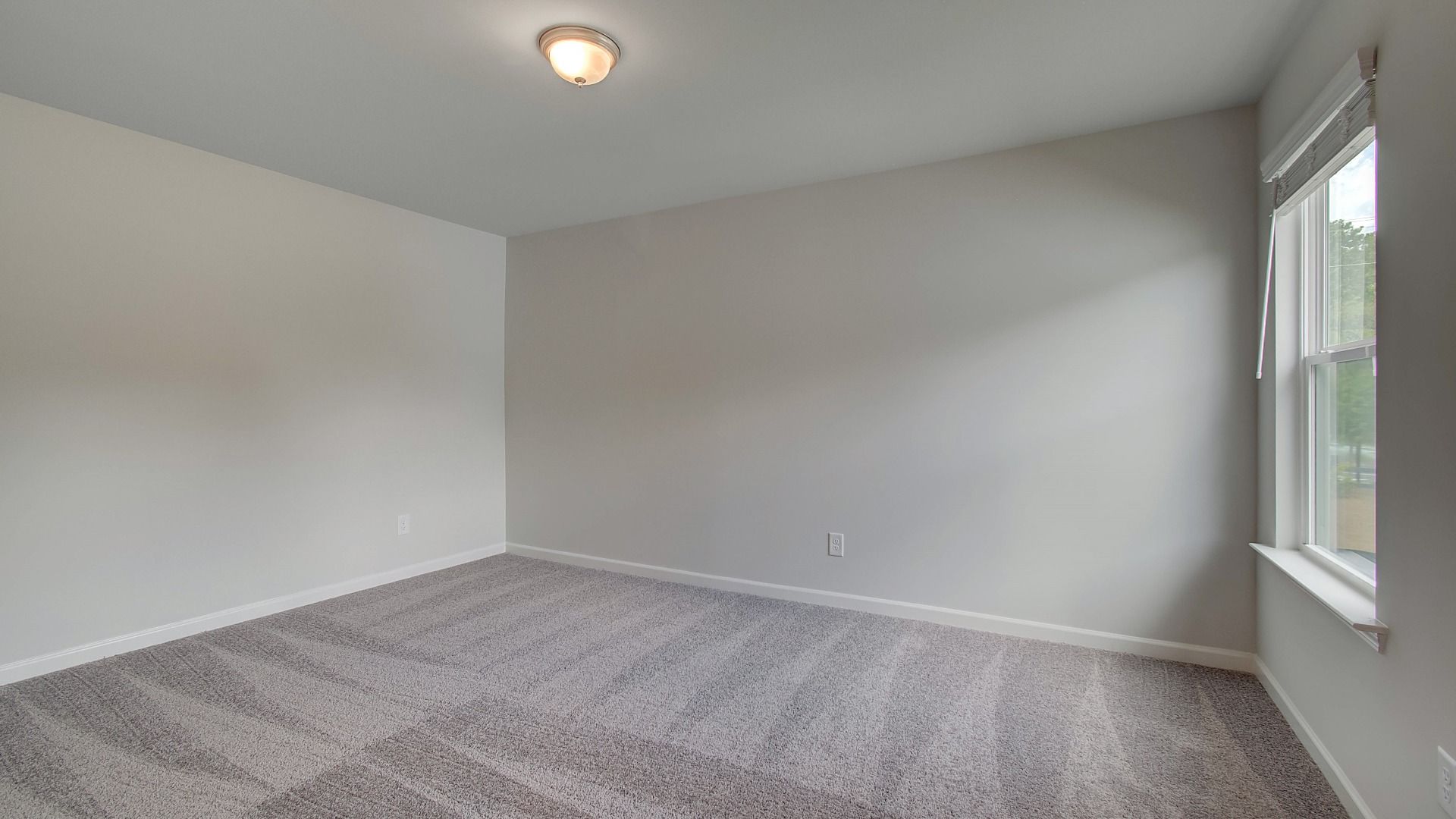Spacious bedroom or office space featuring and abundant natural light from large window in new construction home.