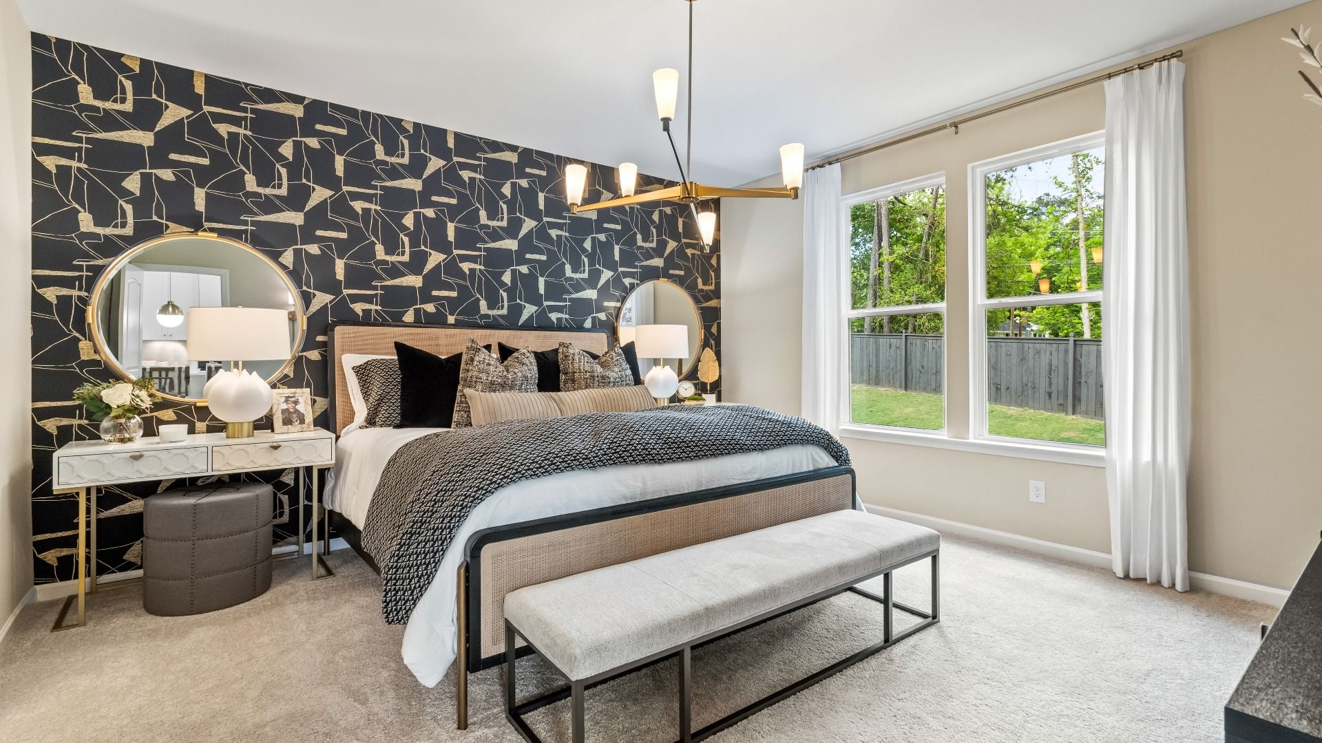 Comfortable first-floor primary suite with large windows and carpet flooring at Enclave at Evergreen in Fairburn, GA.